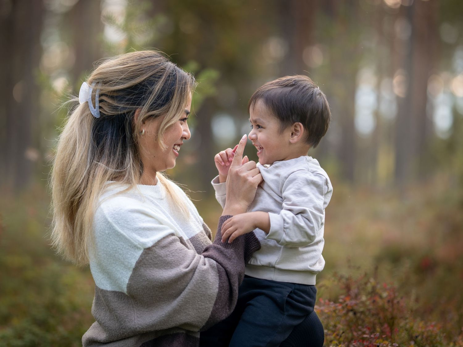 A parent and young child share a joyful moment together while playing outdoors in a misty forest setting.