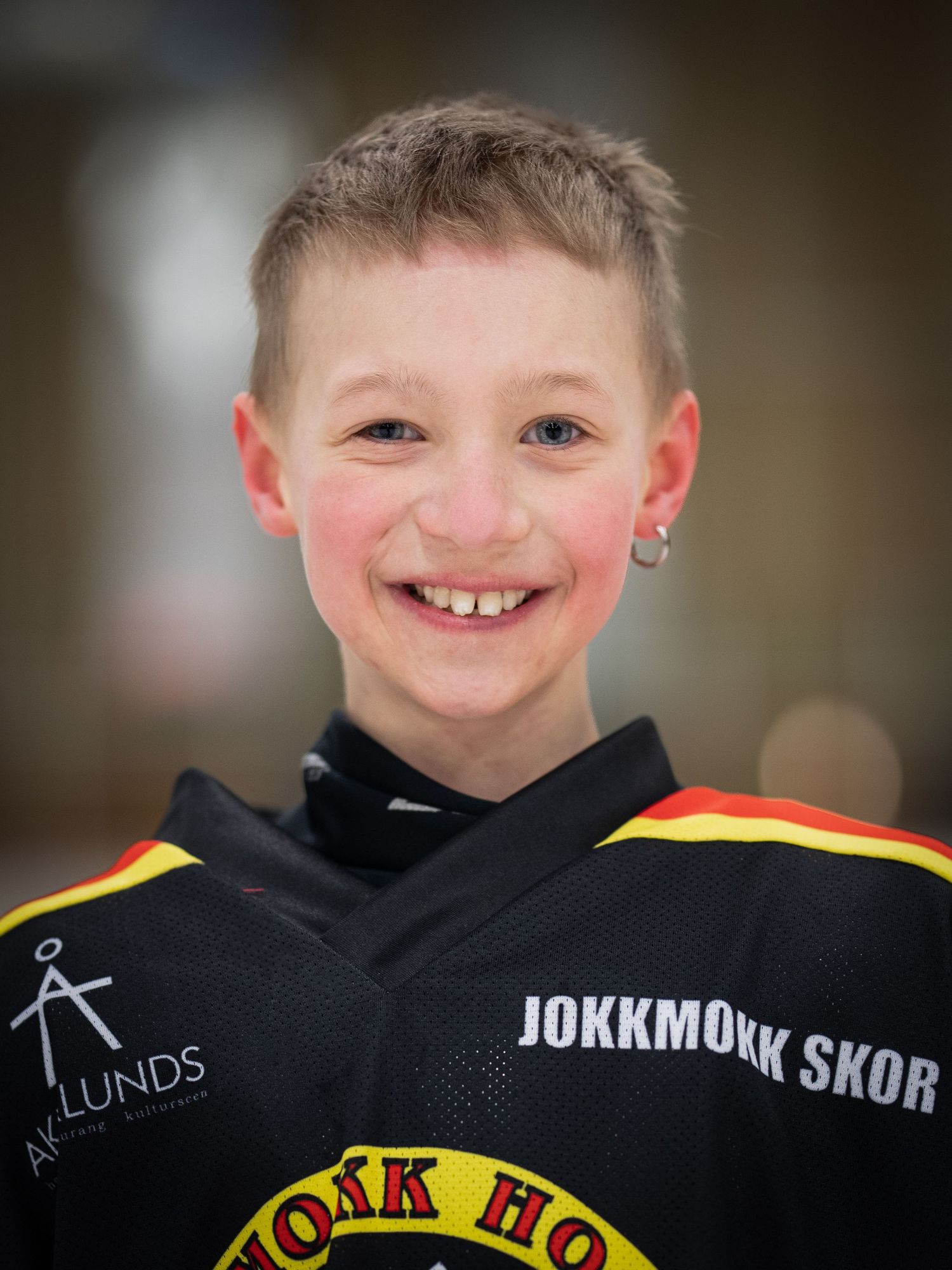 Porträtt av ung hockeyspelare i svart uniform med texten Jokkmokk Skor.