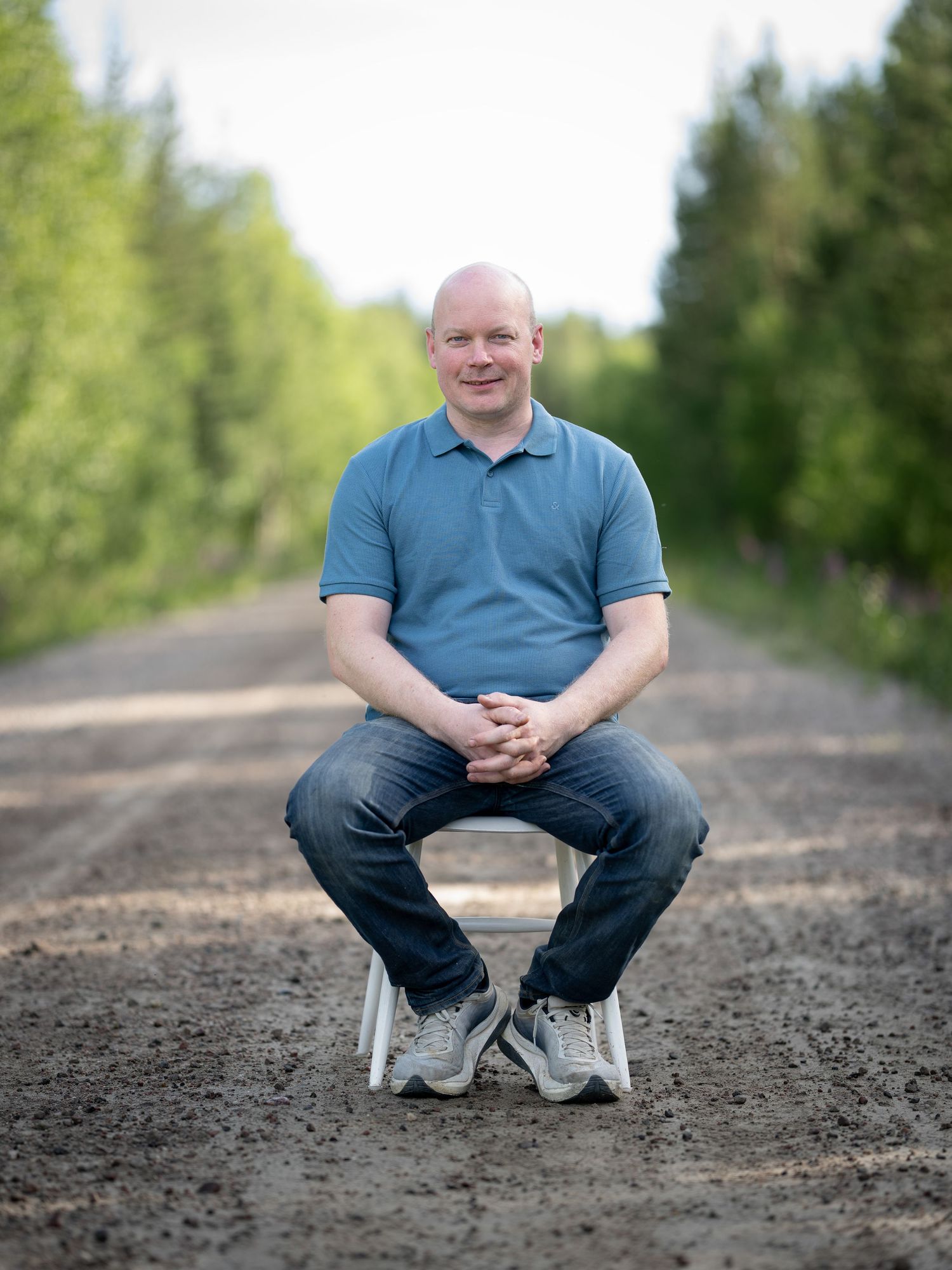 A person in a blue polo shirt sits on a dirt path surrounded by green trees in a series of outdoor portraits.