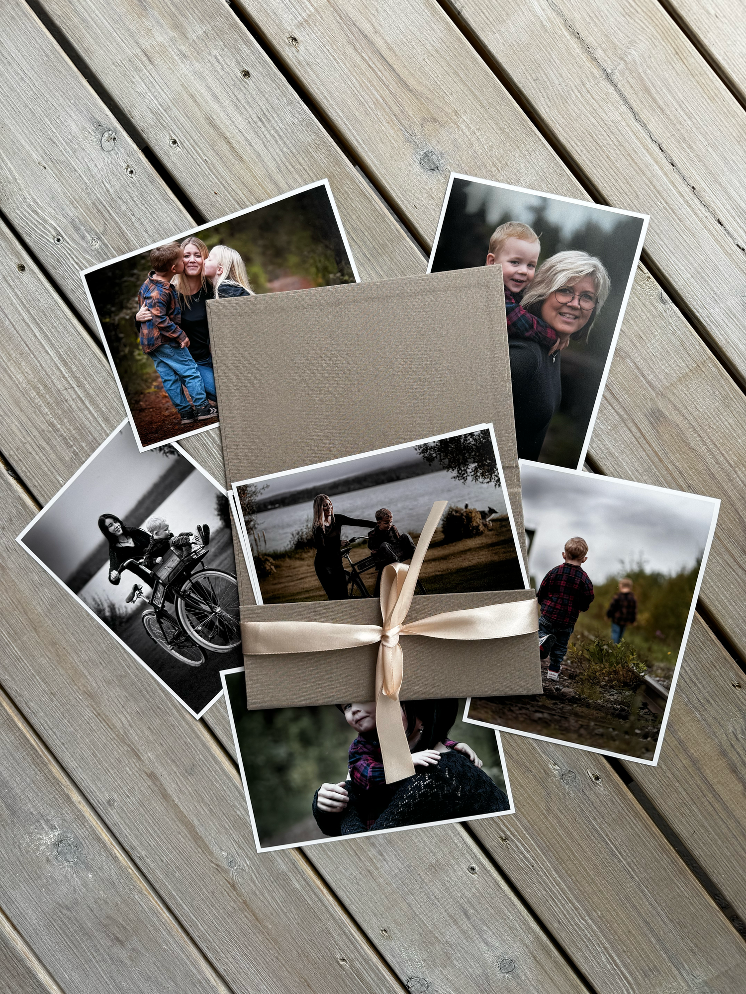 Black and white photographs arranged diagonally on a wooden deck surface in an artistic layout.