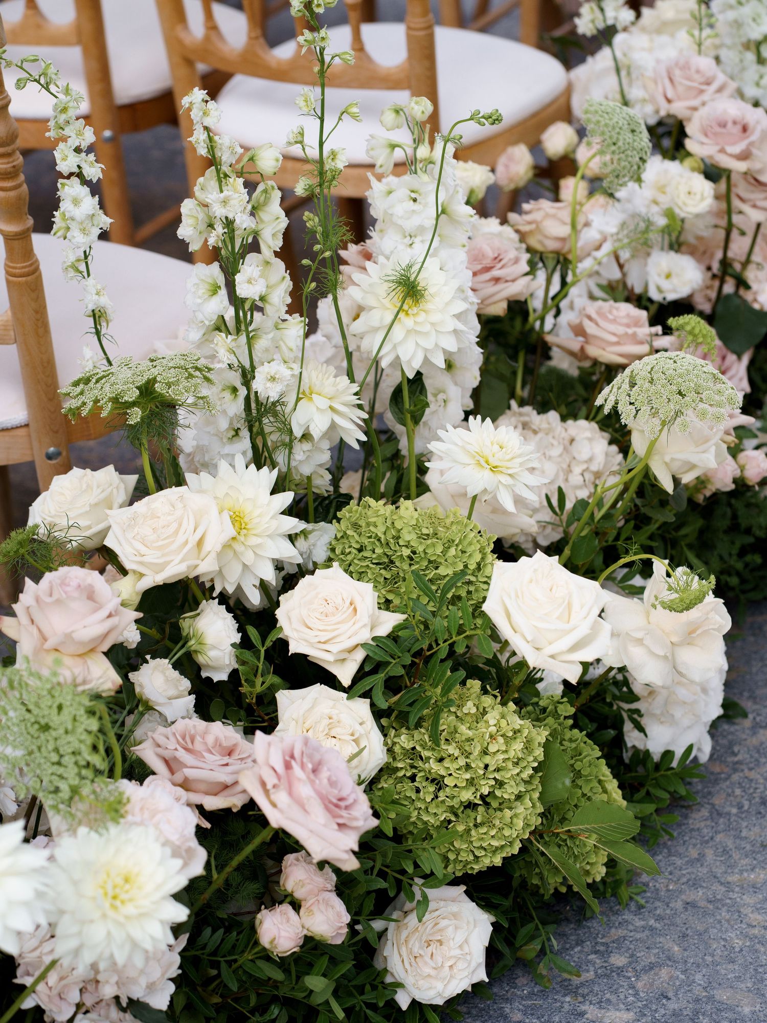 Elegant floral arrangement featuring white dahlias, blush roses, and green hydrangeas in a romantic garden style display.