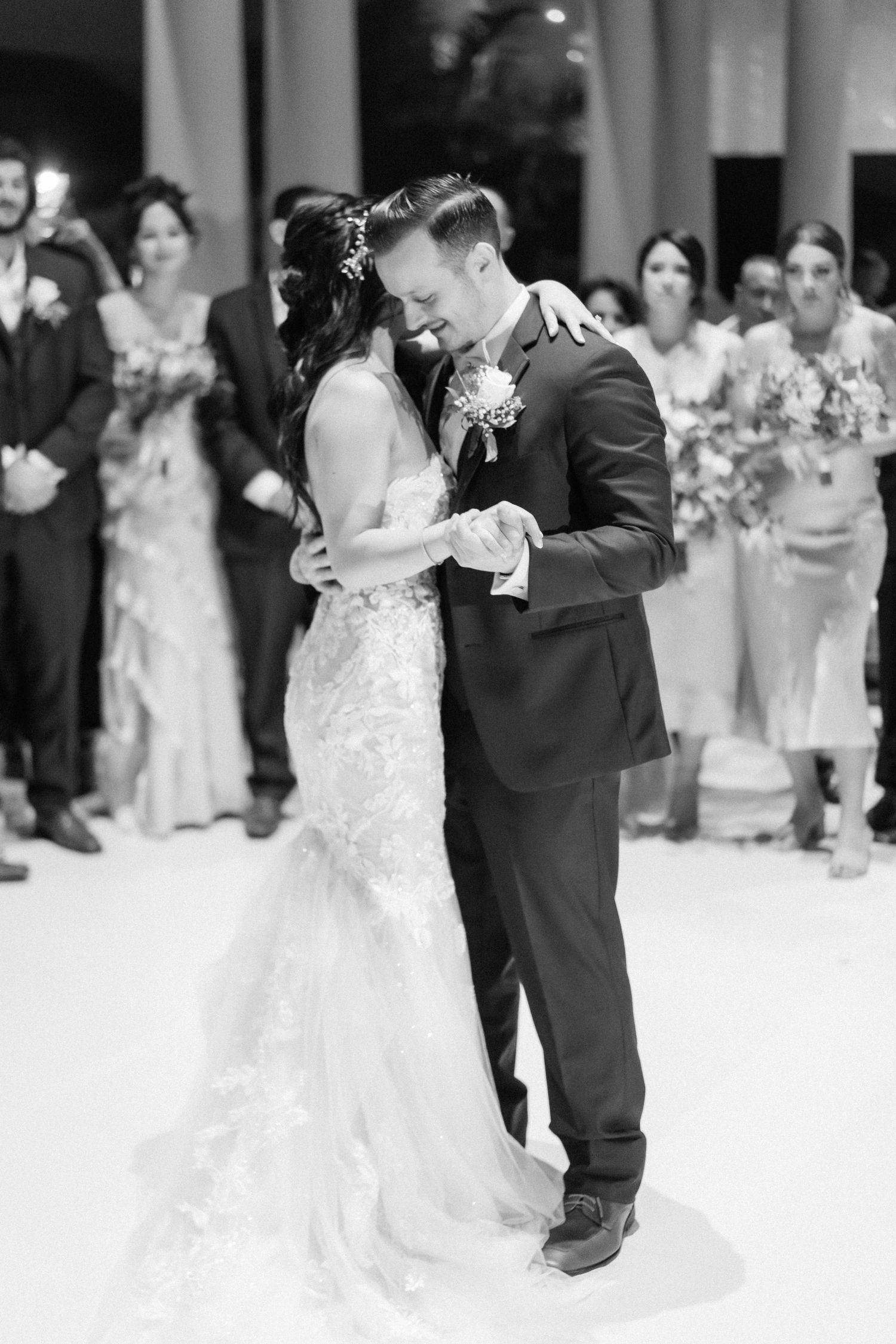 A newlywed couple shares their first dance surrounded by wedding guests.