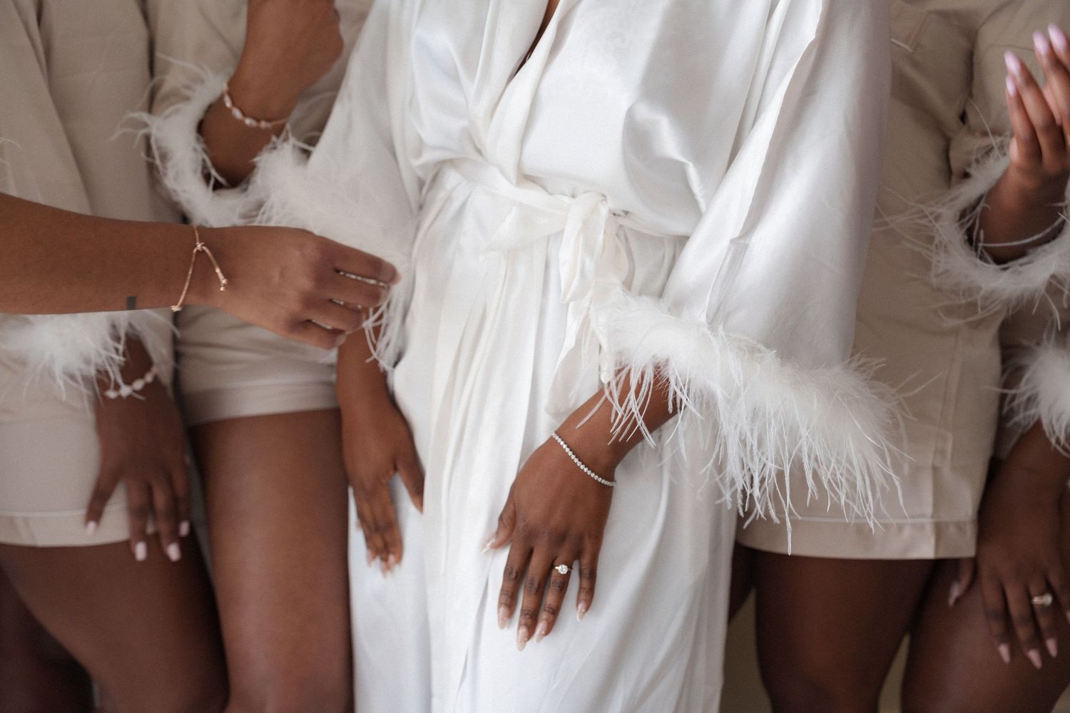 Close up of white feather-trimmed robes worn by the bridal party.