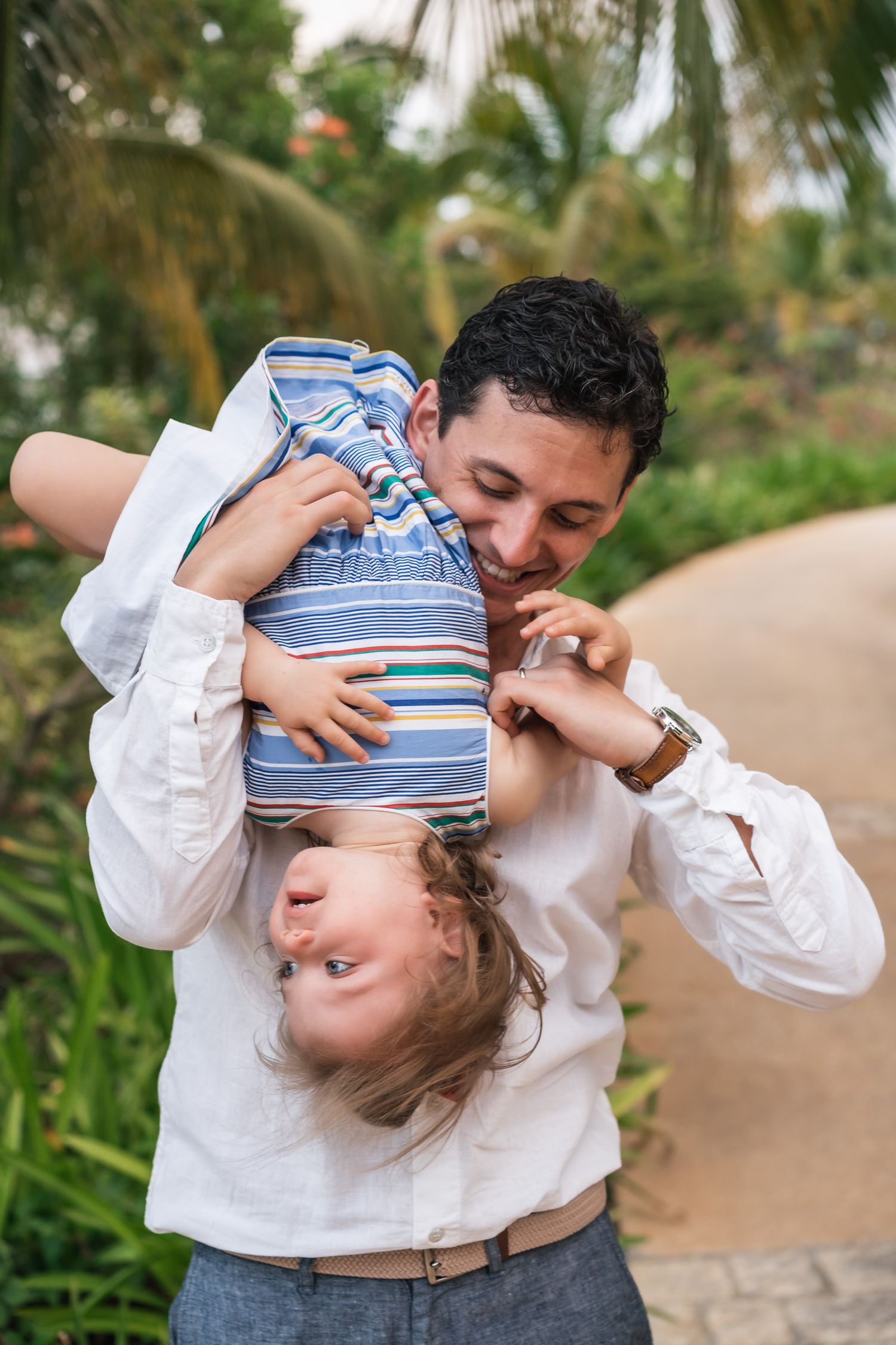 Playful moment between parent and child in matching outfits on a garden path.