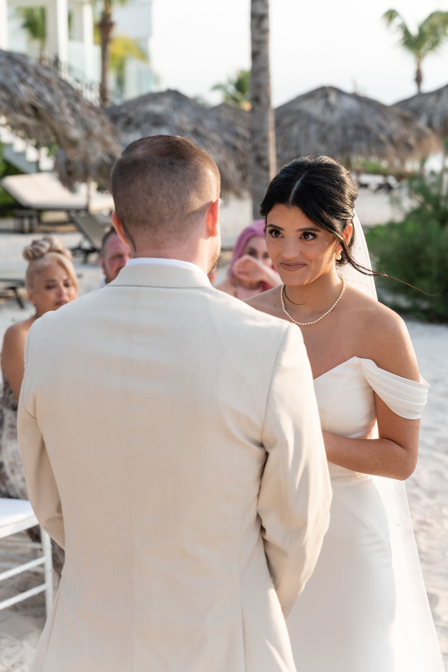 A tender moment during a beach wedding ceremony with palm trees in the background.