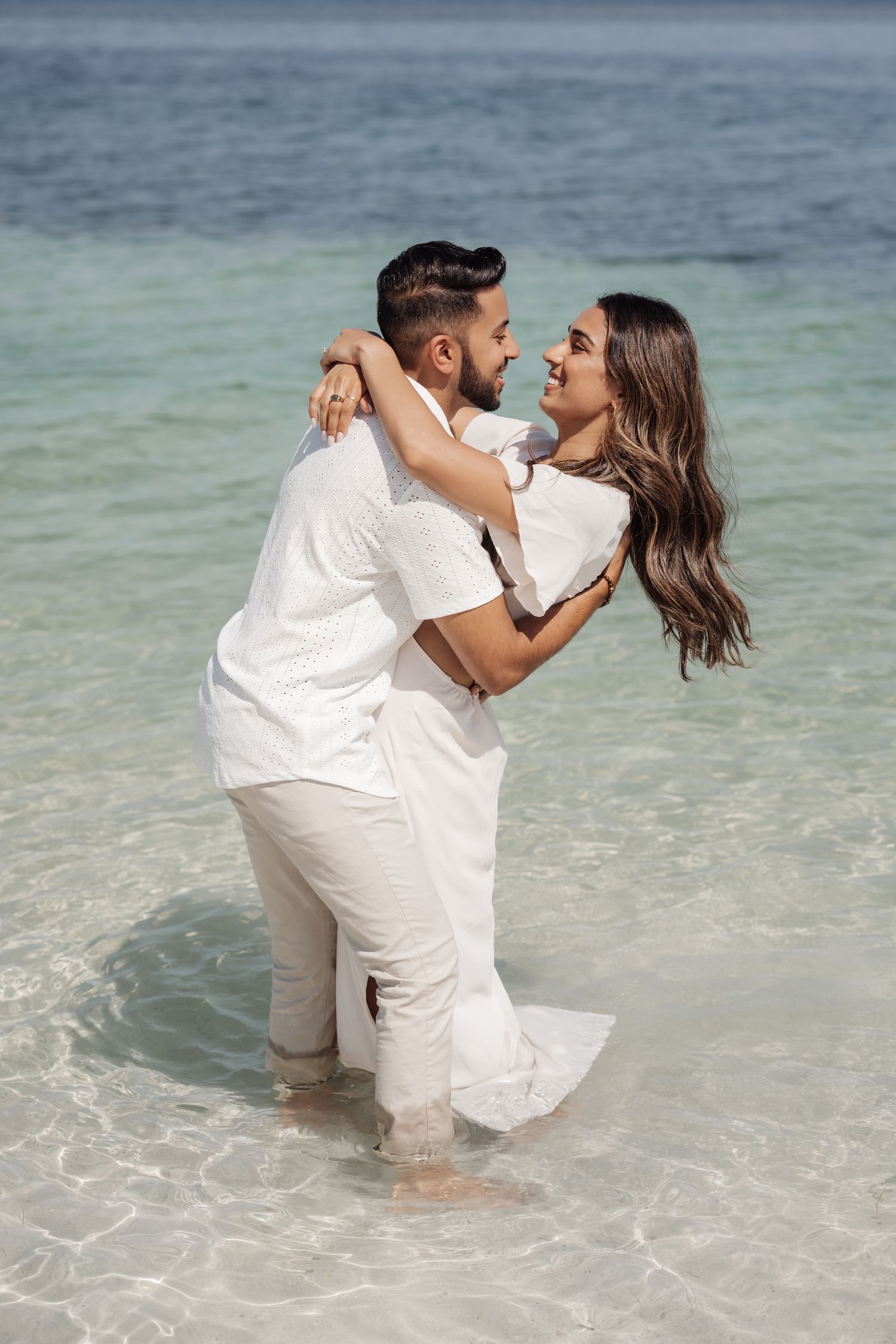 A couple sharing a passionate embrace while standing in crystal clear ocean waters.