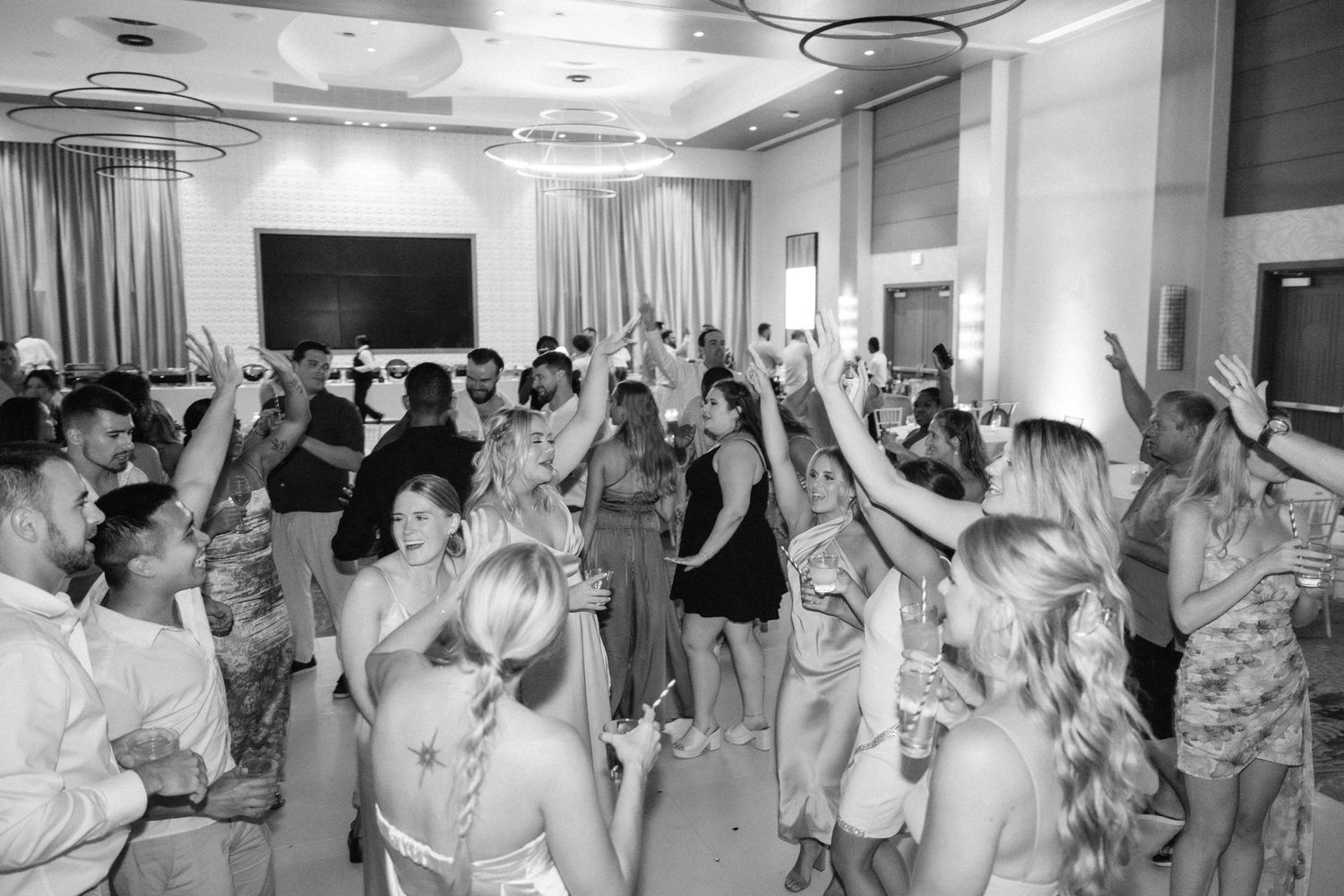 Wedding reception guests dancing and celebrating on a festively lit dance floor.