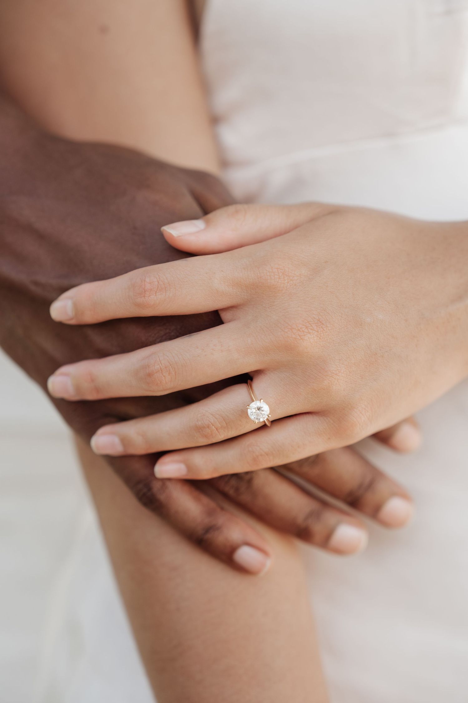 Close up of hands with engagement ring showing tender moment between couple.