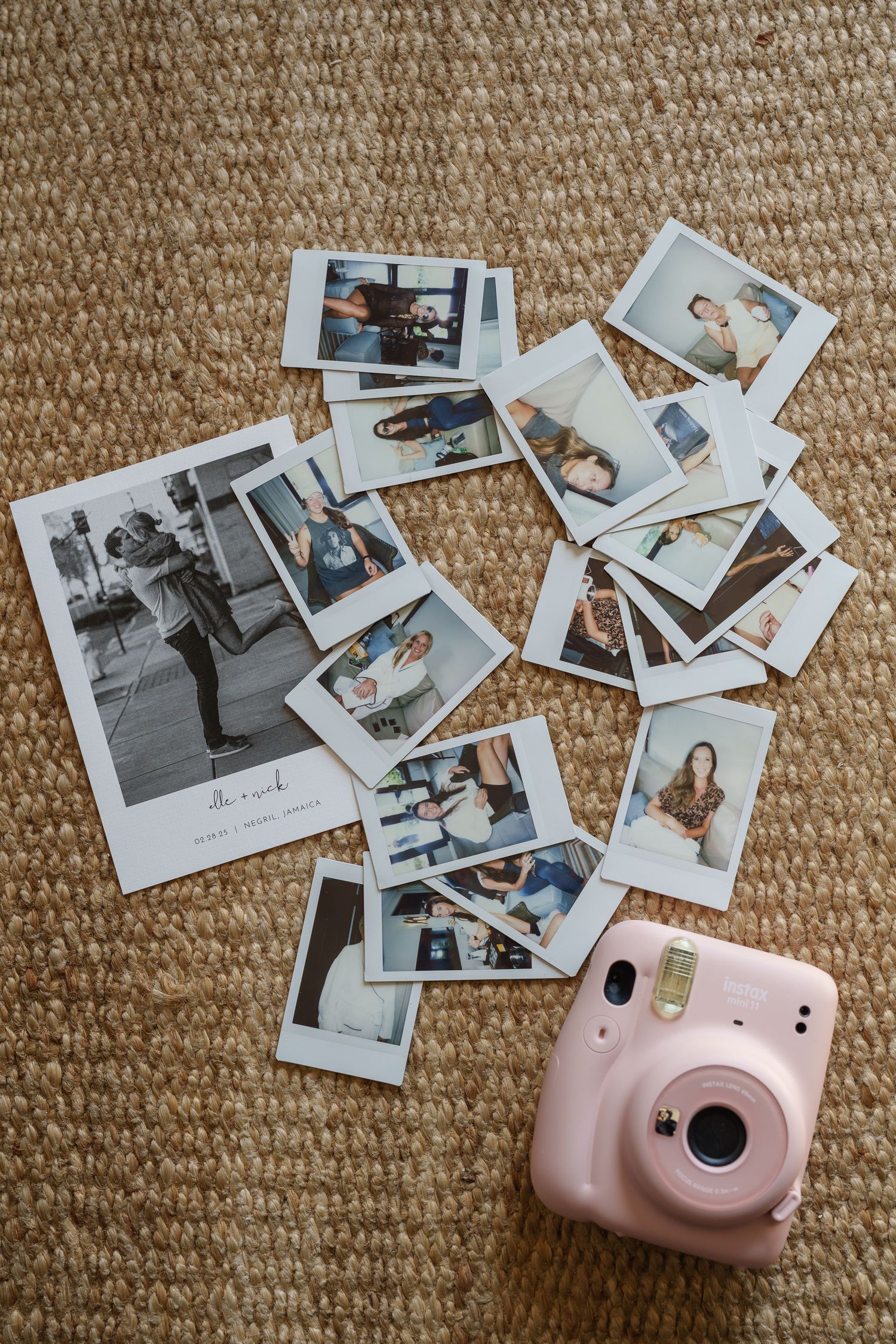 A pink Fujifilm Instax Mini instant camera surrounded by scattered polaroid photos on a beige carpet.