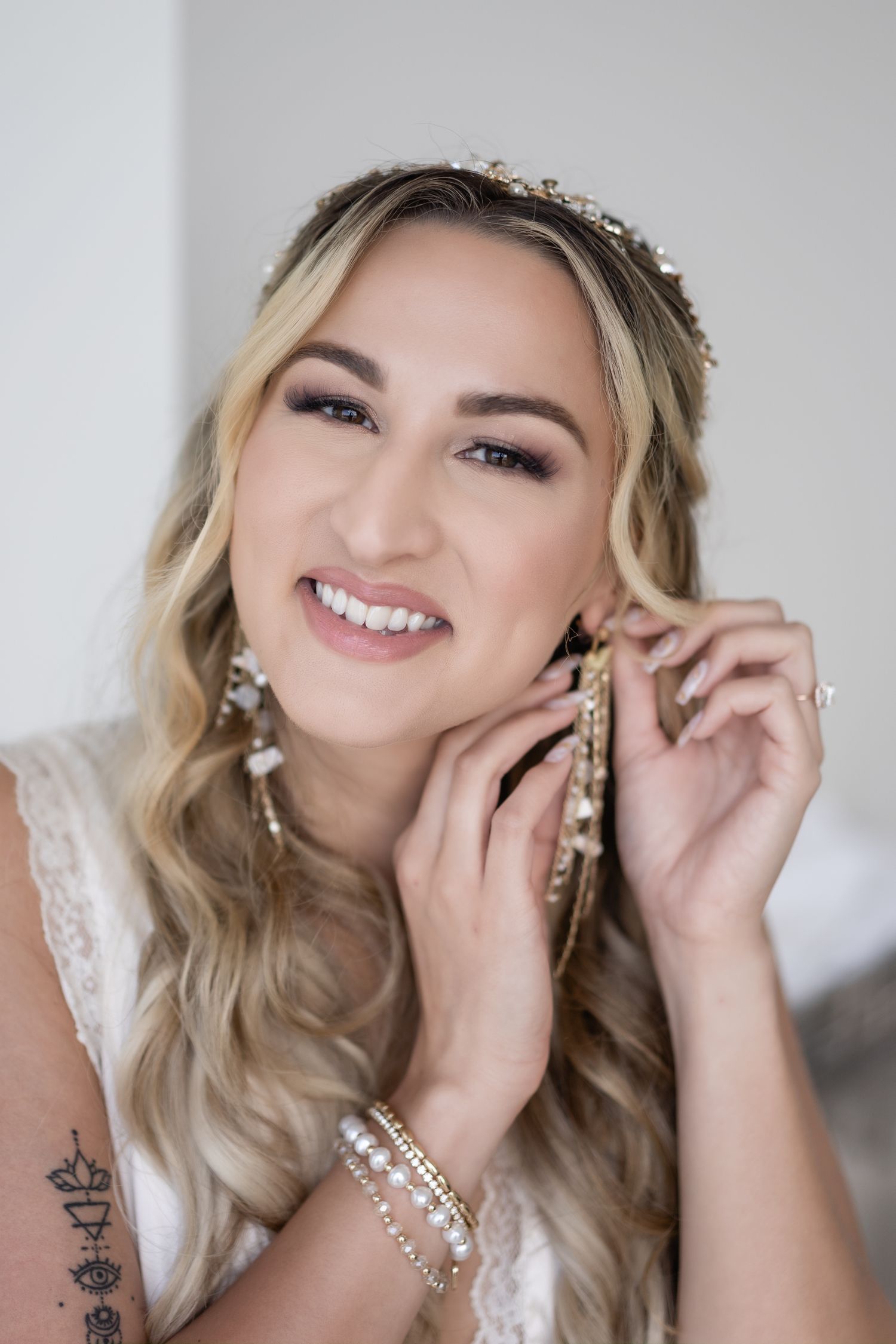 Close up of bride wearing pearl headpiece and earrings with soft makeup and blonde waves.