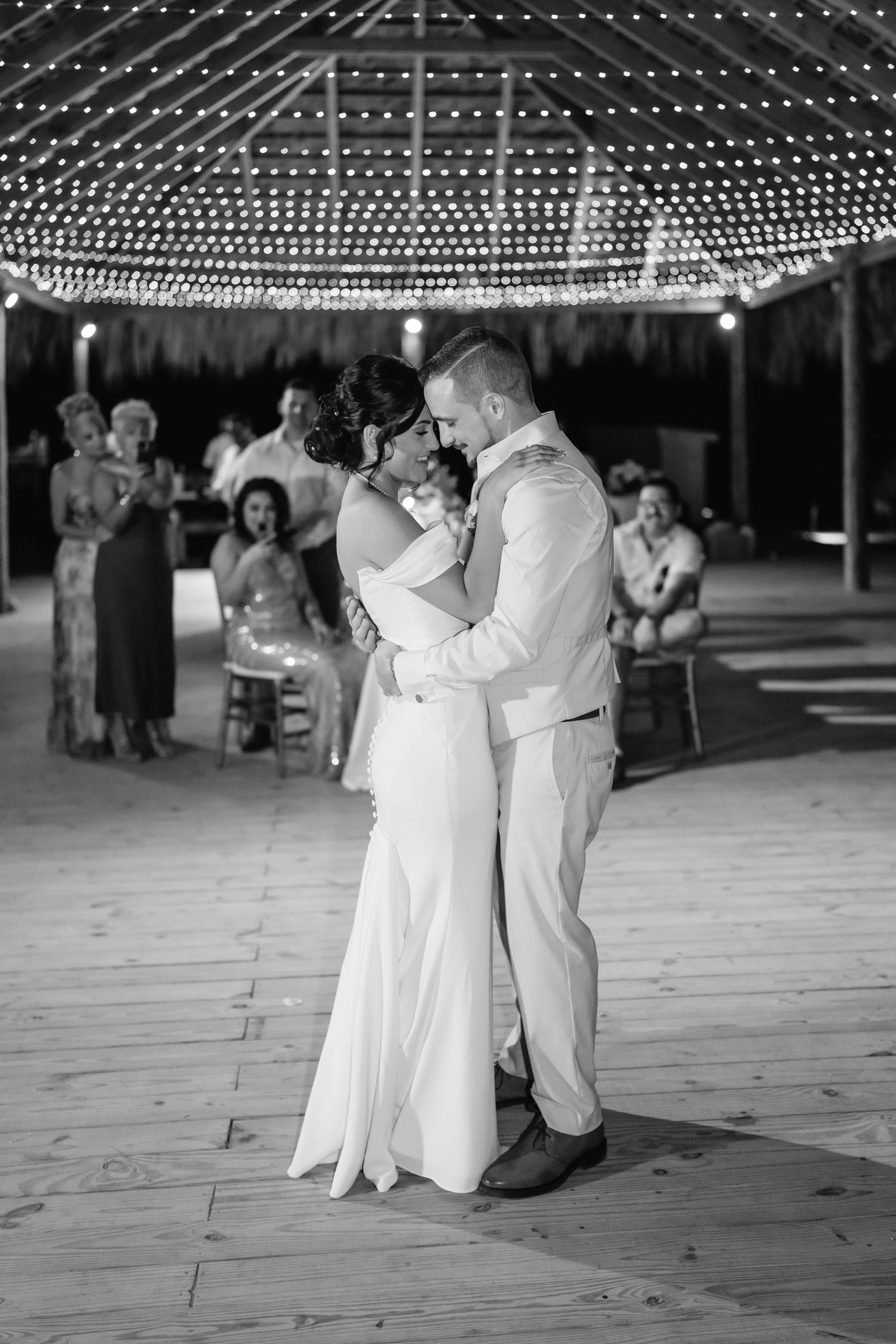 A romantic first dance under twinkling string lights at an outdoor wedding reception.