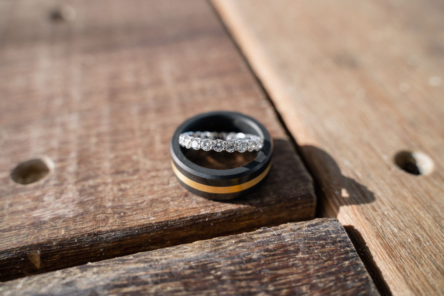 Wedding rings photographed on rustic wooden surface.