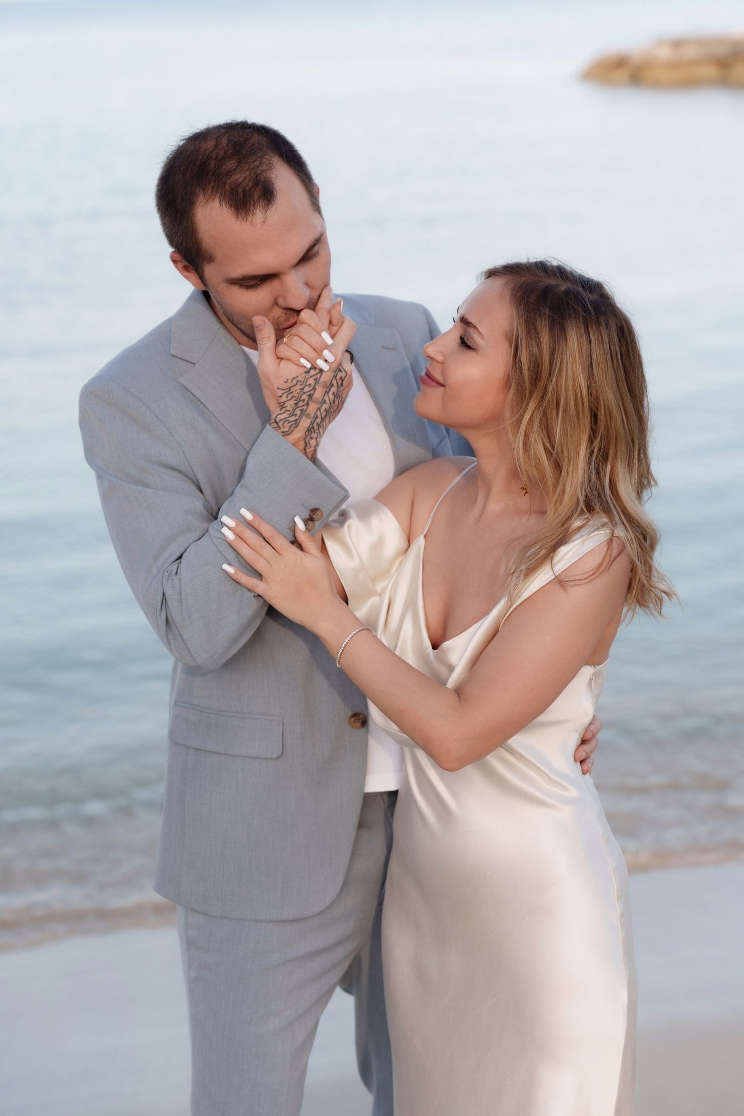 A tender moment between newlyweds against an ocean backdrop.