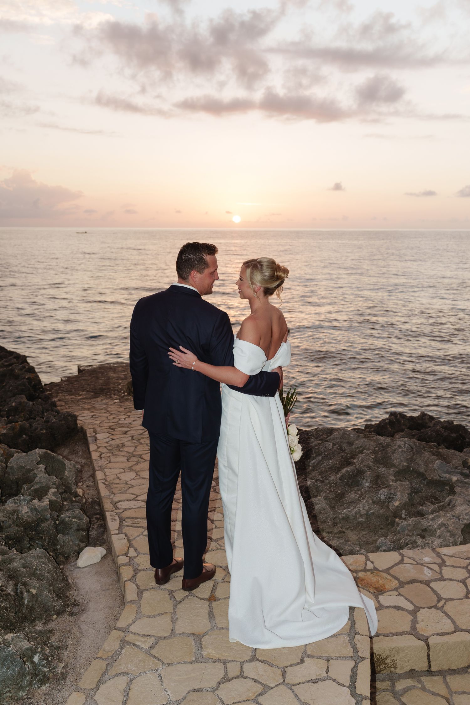 A couple on cliff with ocean backdrop at golden hour Negril Jamaica wedding