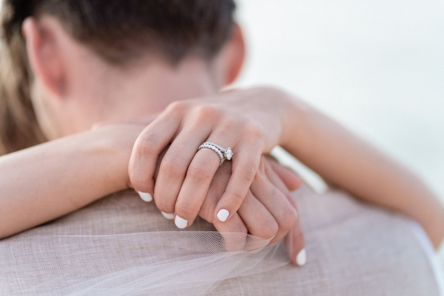 Close-up detail shot of wedding rings during an embrace with manicured nails.
