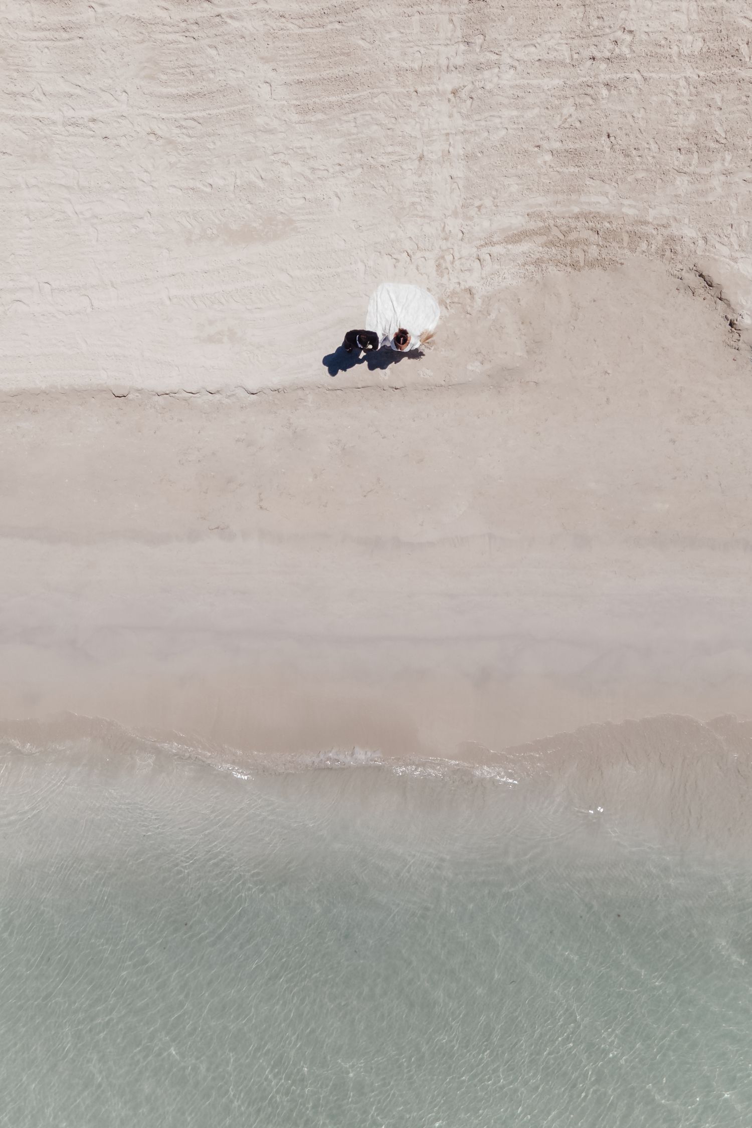 Aerial view of turquoise ocean water meeting sandy beach shoreline.