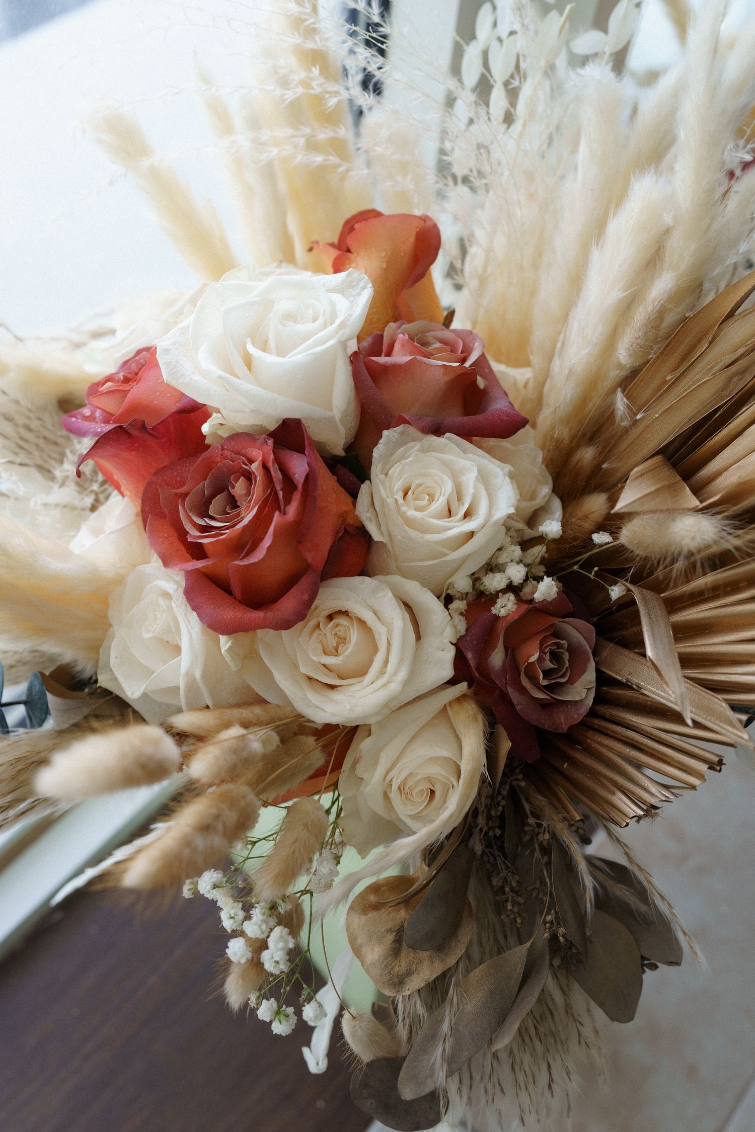 Elegant bridal bouquet with white and coral roses mixed with dried pampas grass and baby's breath.