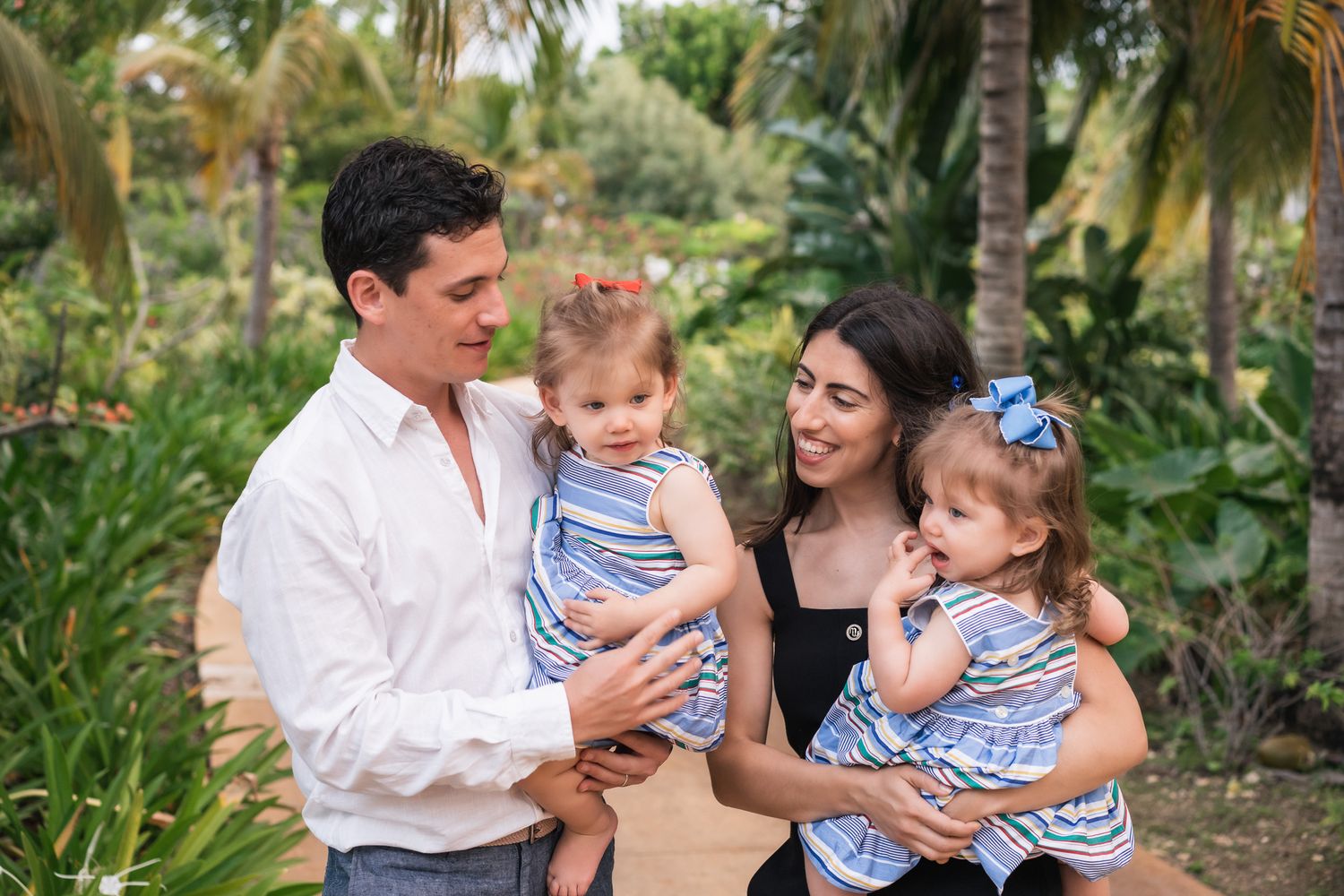 Family portrait in a lush tropical garden setting wearing coordinated blue and white outfits.