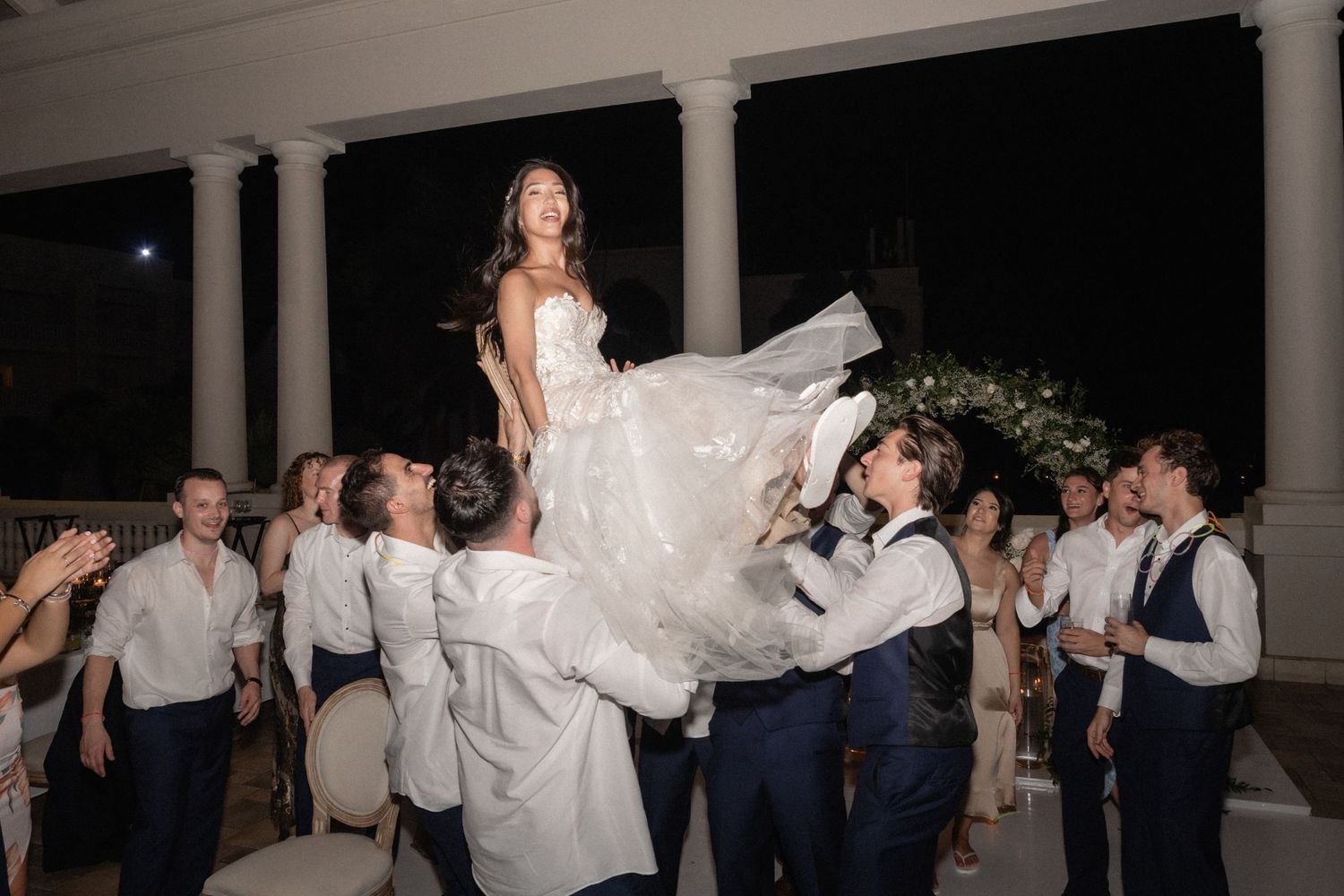 Wedding celebration moment with guests lifting the bride during a reception dance.