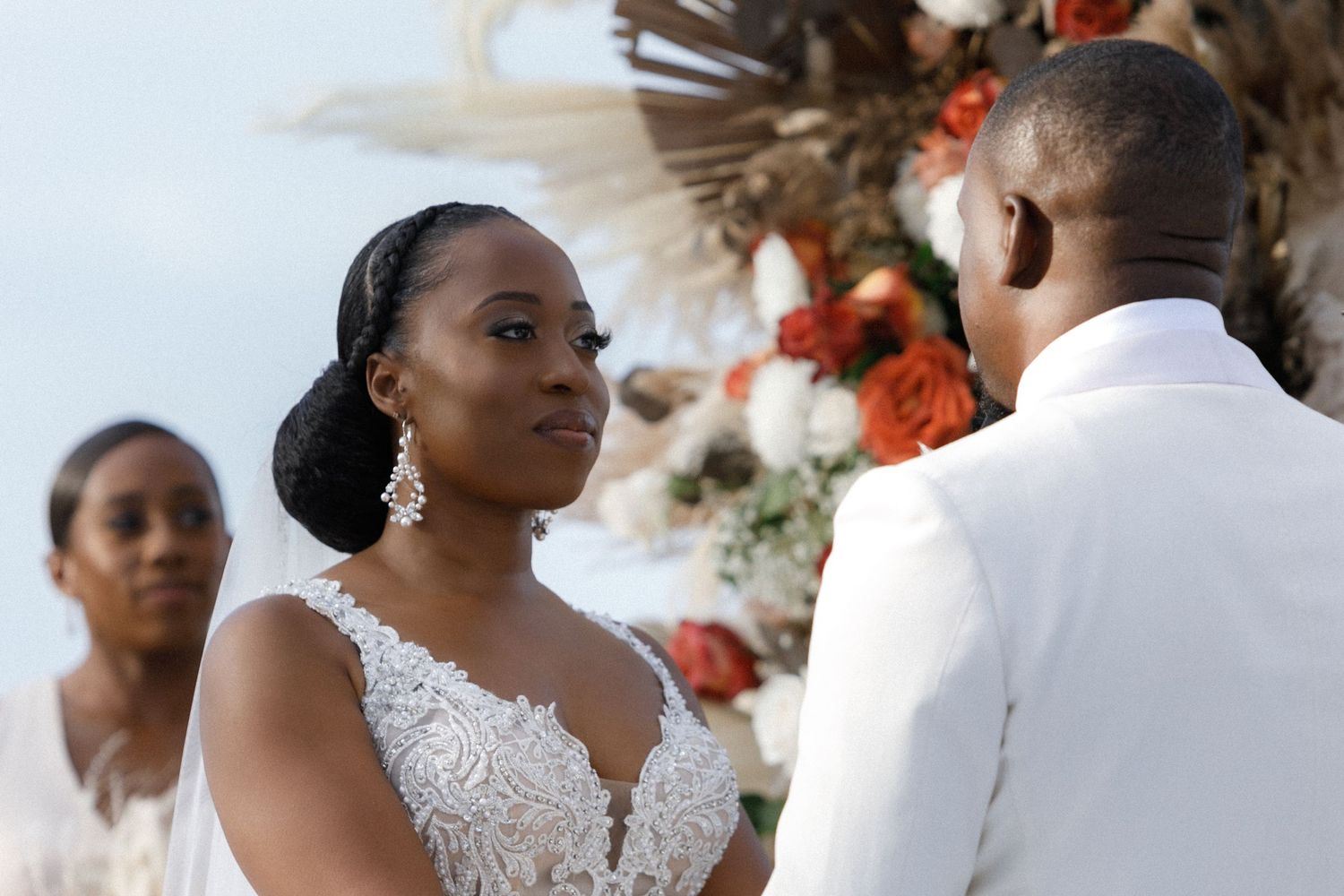 A romantic wedding ceremony under a floral arch with elegant white and orange decor.