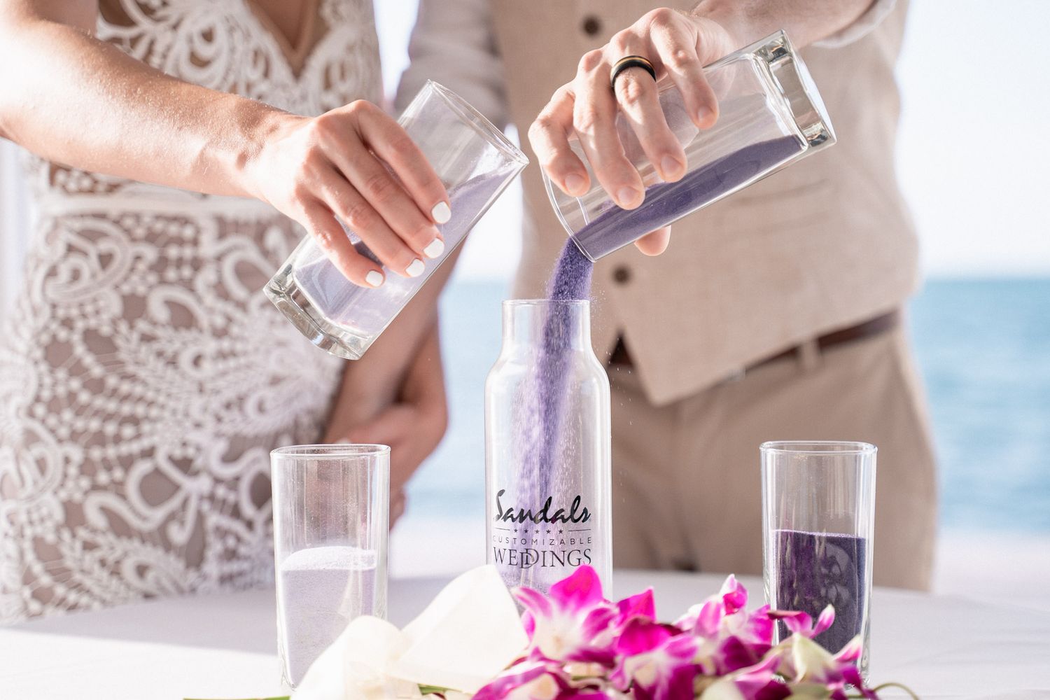Purple sand ceremony with orchid decorations at a beach wedding.