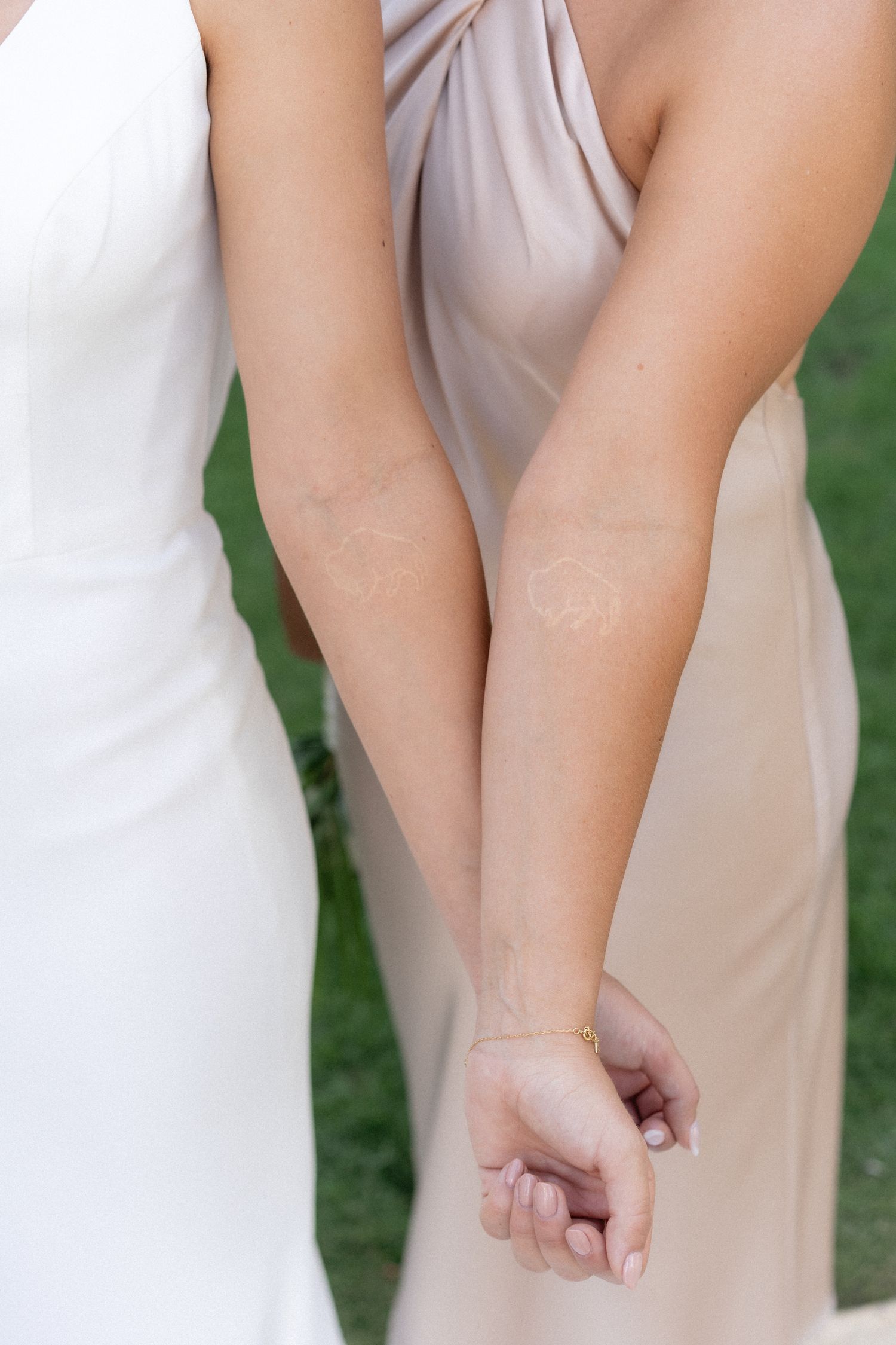Close up detail of white and blush bridesmaid dresses against a green lawn background.
