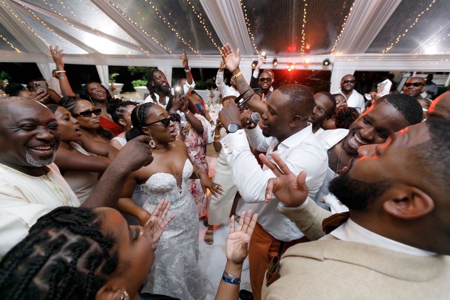 Guests celebrate with enthusiasm in a circle on the dance floor at a wedding reception.