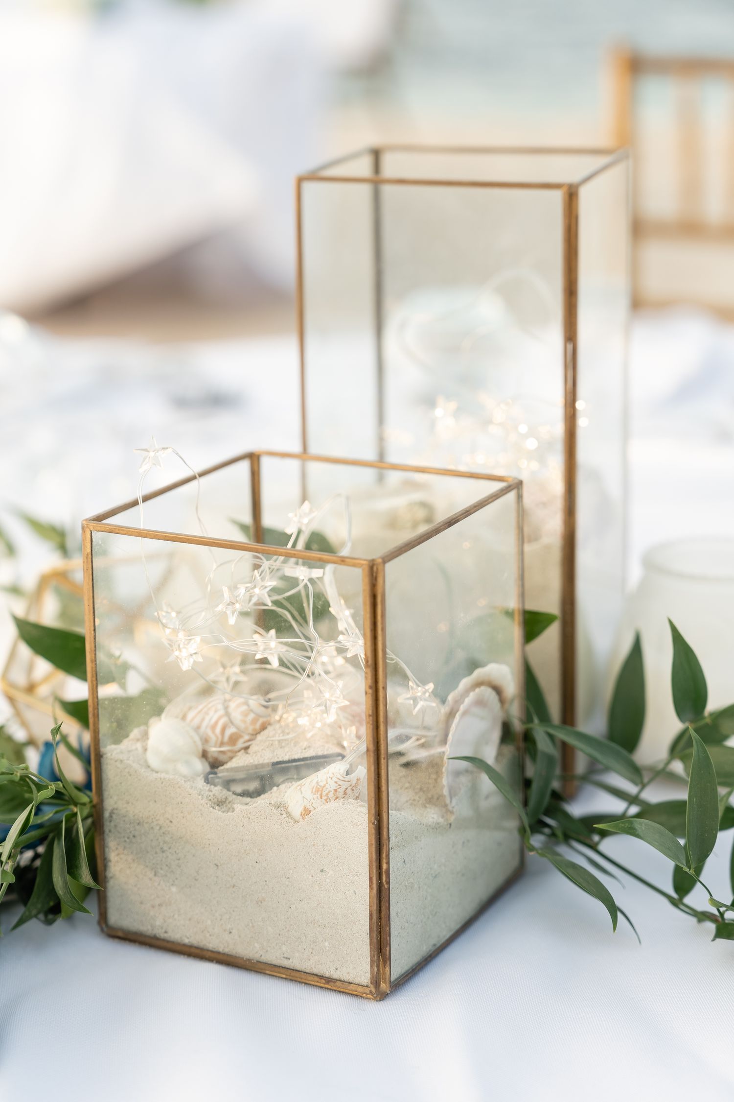 Modern geometric glass terrariums with white flowers and greenery as wedding centerpieces.