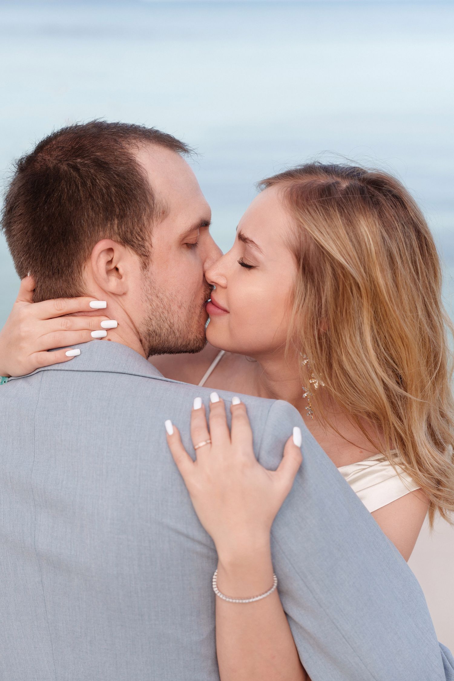 Romantic couple in intimate embrace sharing a kiss with a light background.