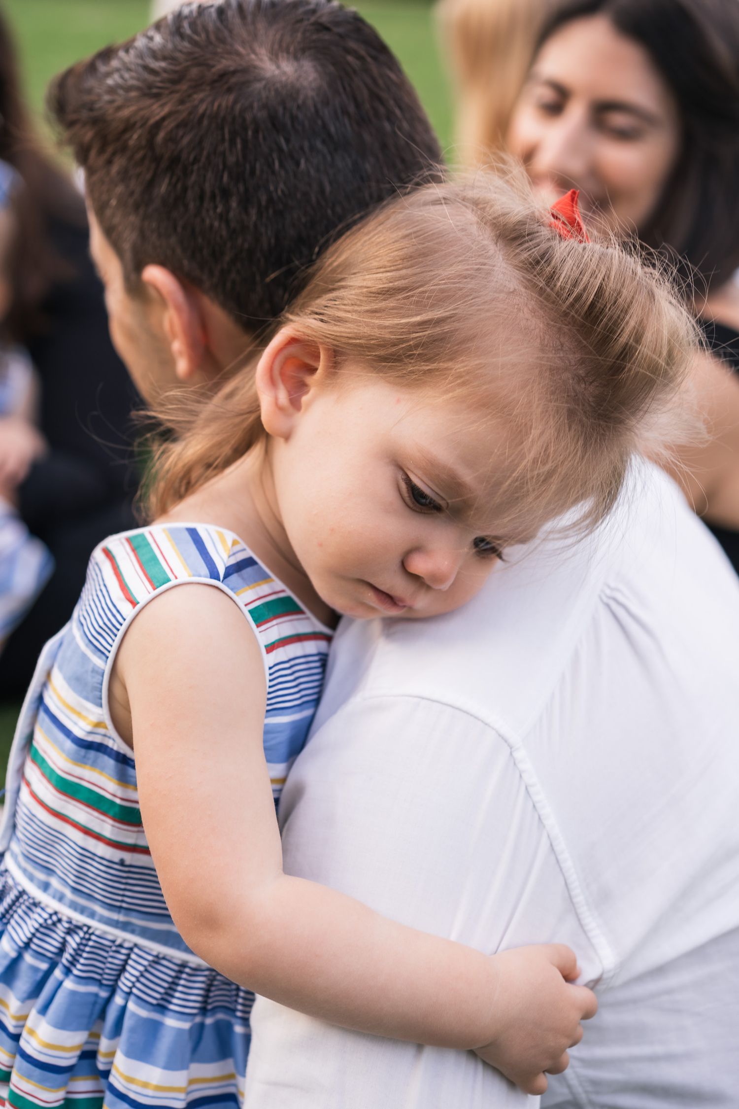 Tender moment captured during family gathering on green lawn.