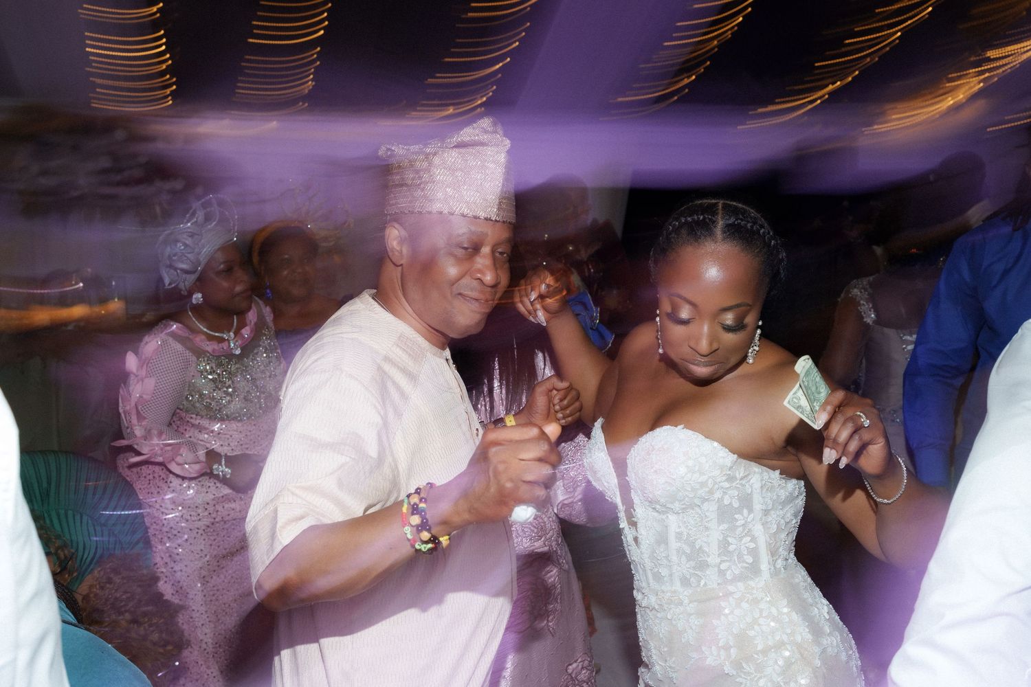 Dynamic reception dance floor moment captured with purple lighting effects.