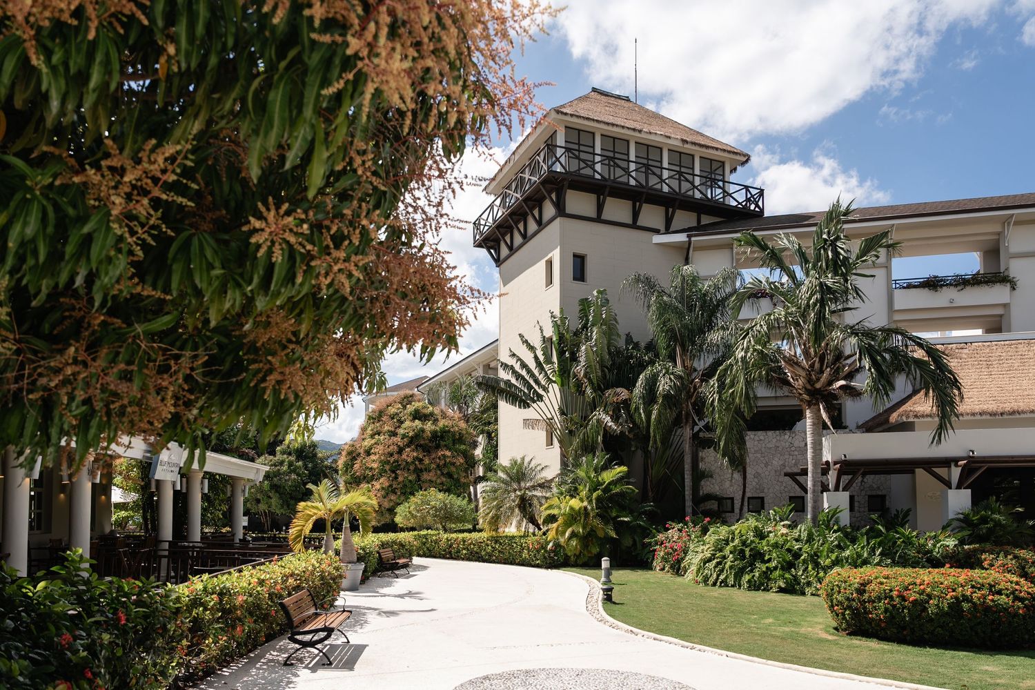 Elegant white resort building with Mediterranean architecture surrounded by lush tropical landscaping.