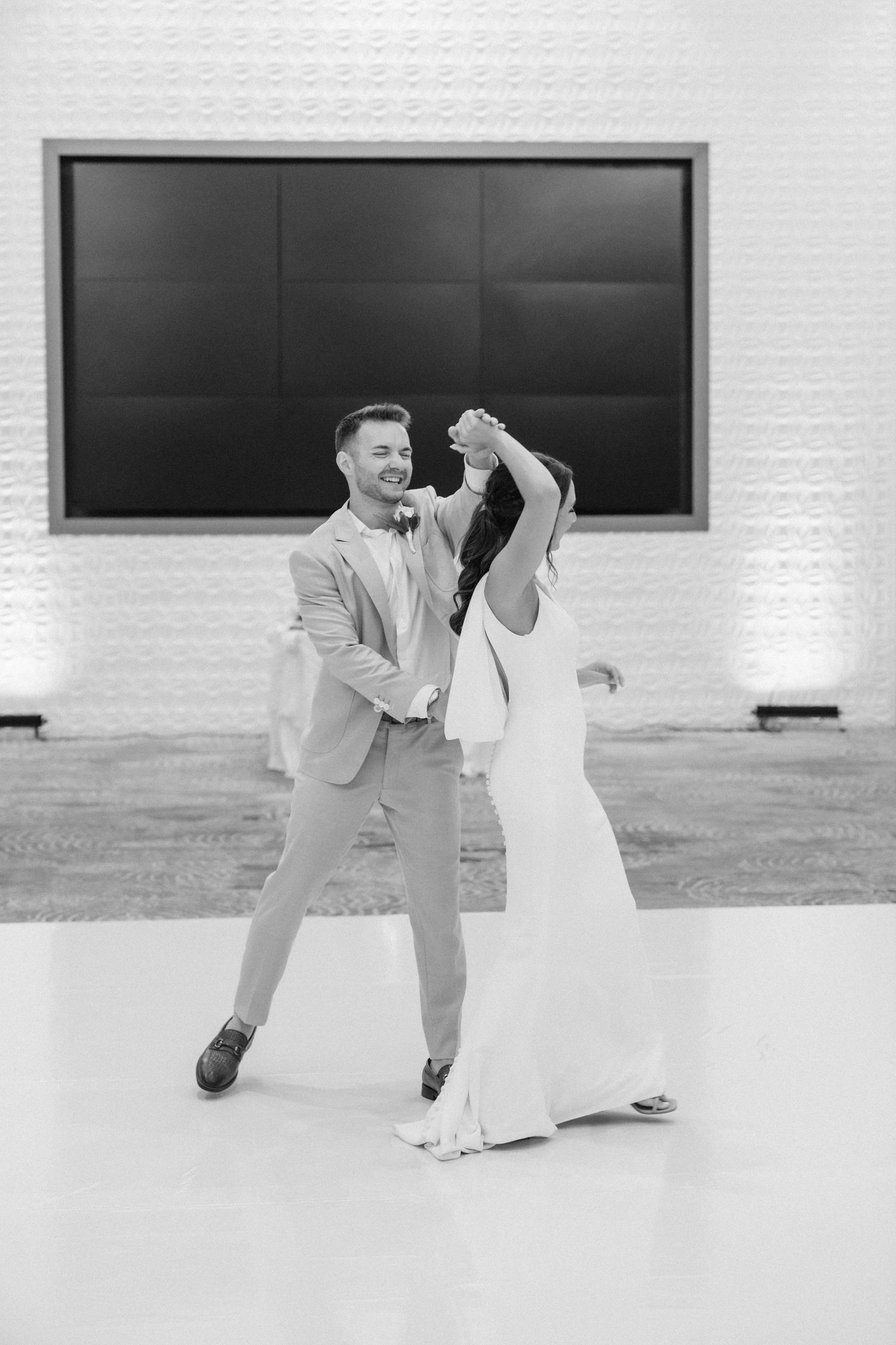 A black and white photo captures a couple's first dance at their wedding reception.