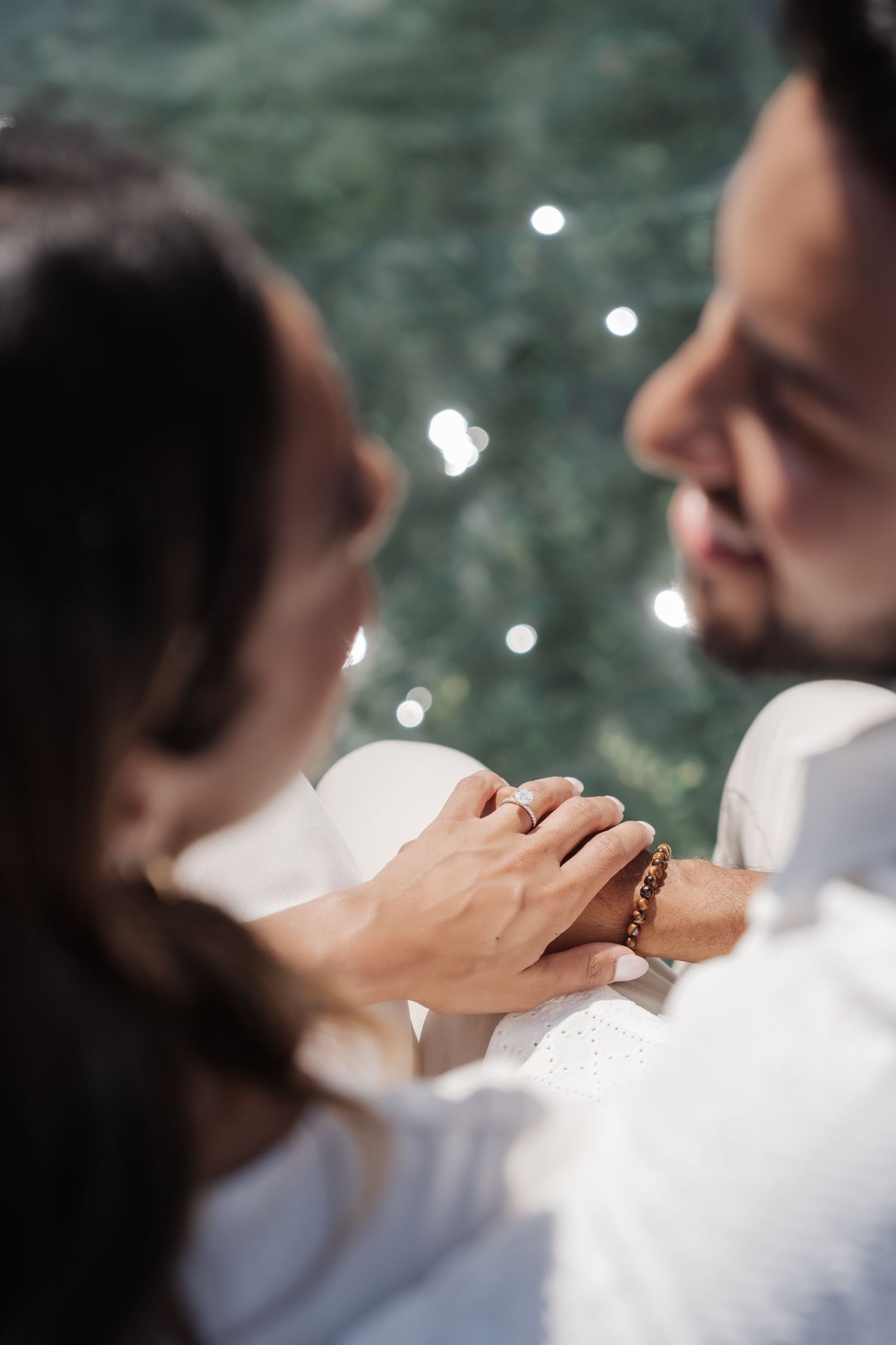 Close-up of hands with sparkling water bokeh in the background.