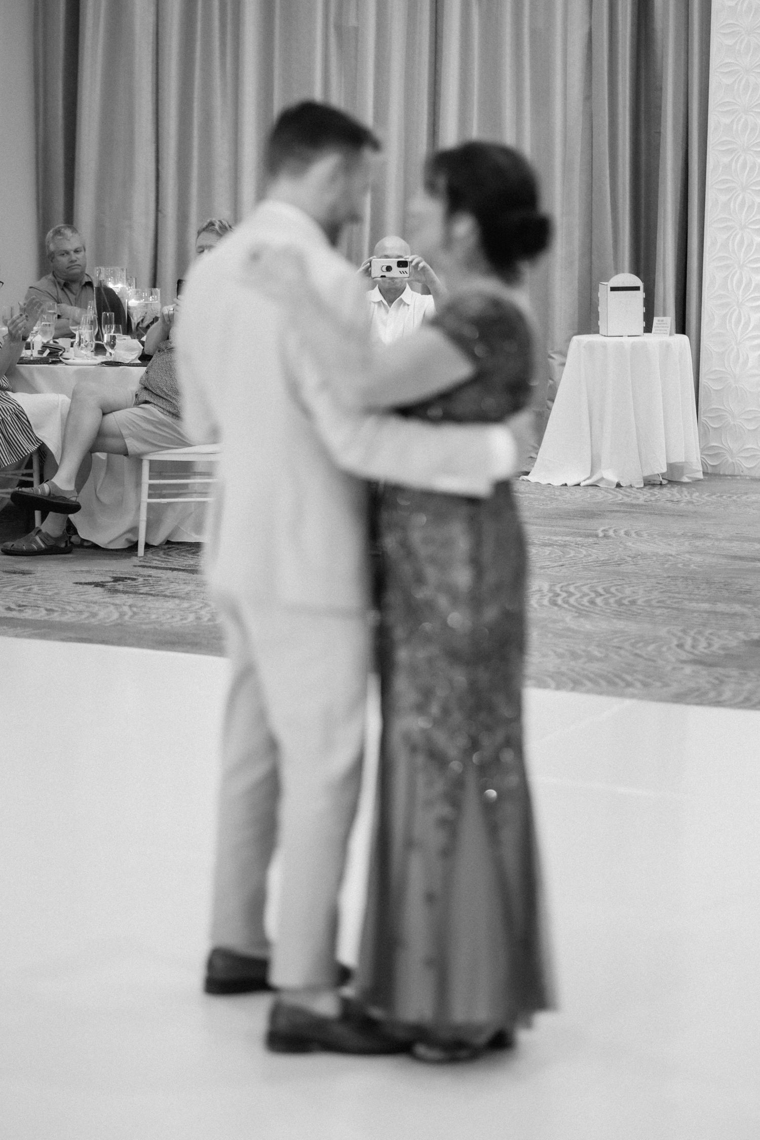 A couple sharing an intimate dance moment in black and white at an elegant reception.