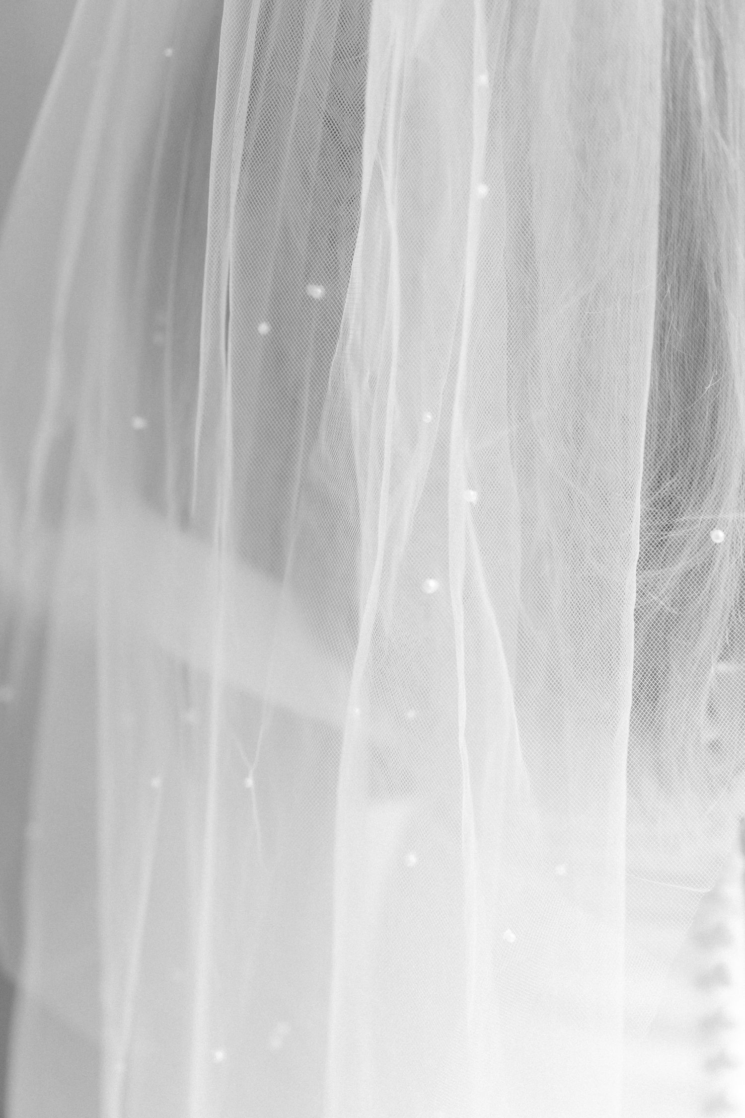 Close-up detail of delicate white wedding veil fabric with soft sparkles and texture.