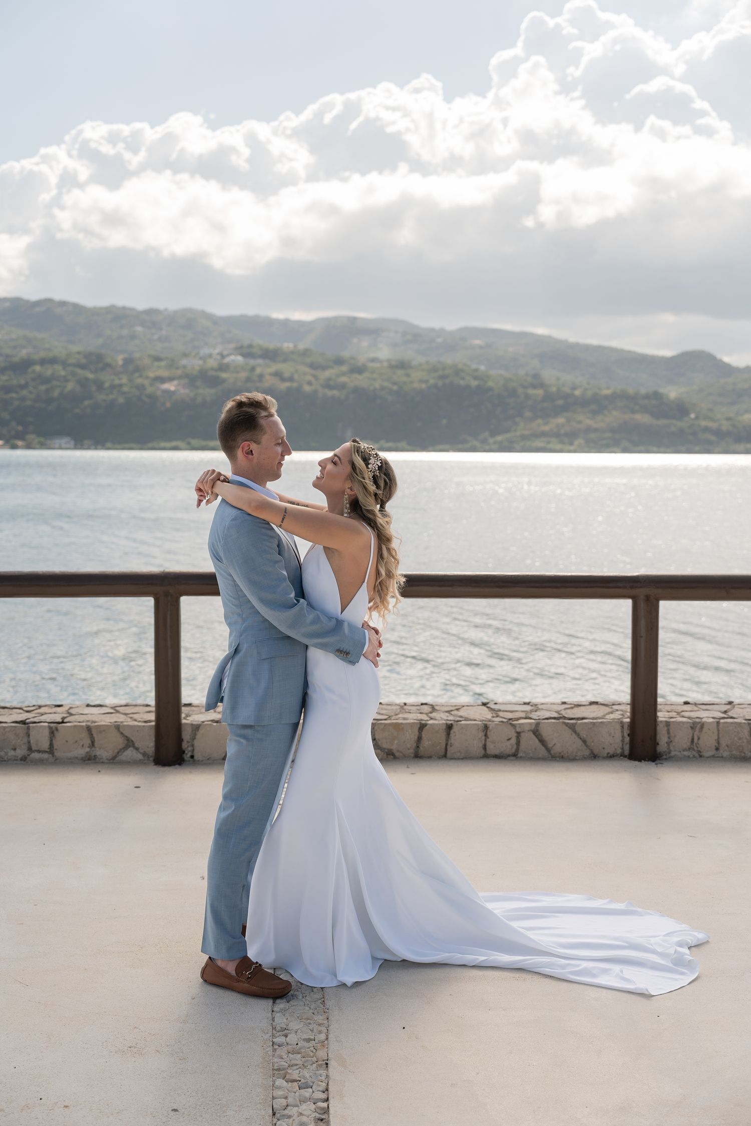 A romantic embrace on a waterfront terrace with mountains in the background.