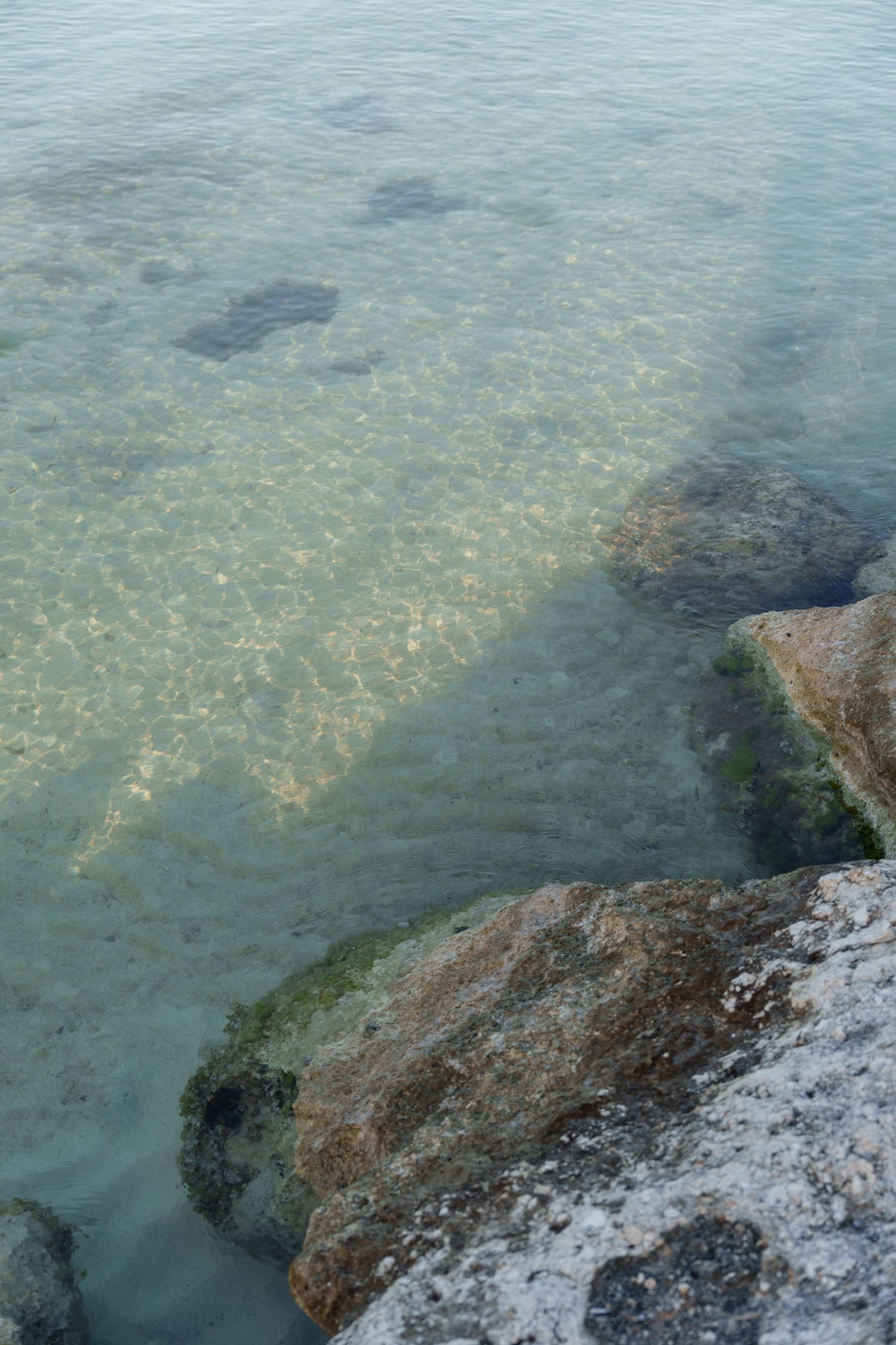 Clear turquoise water revealing rocky seabed formations near the coastline.