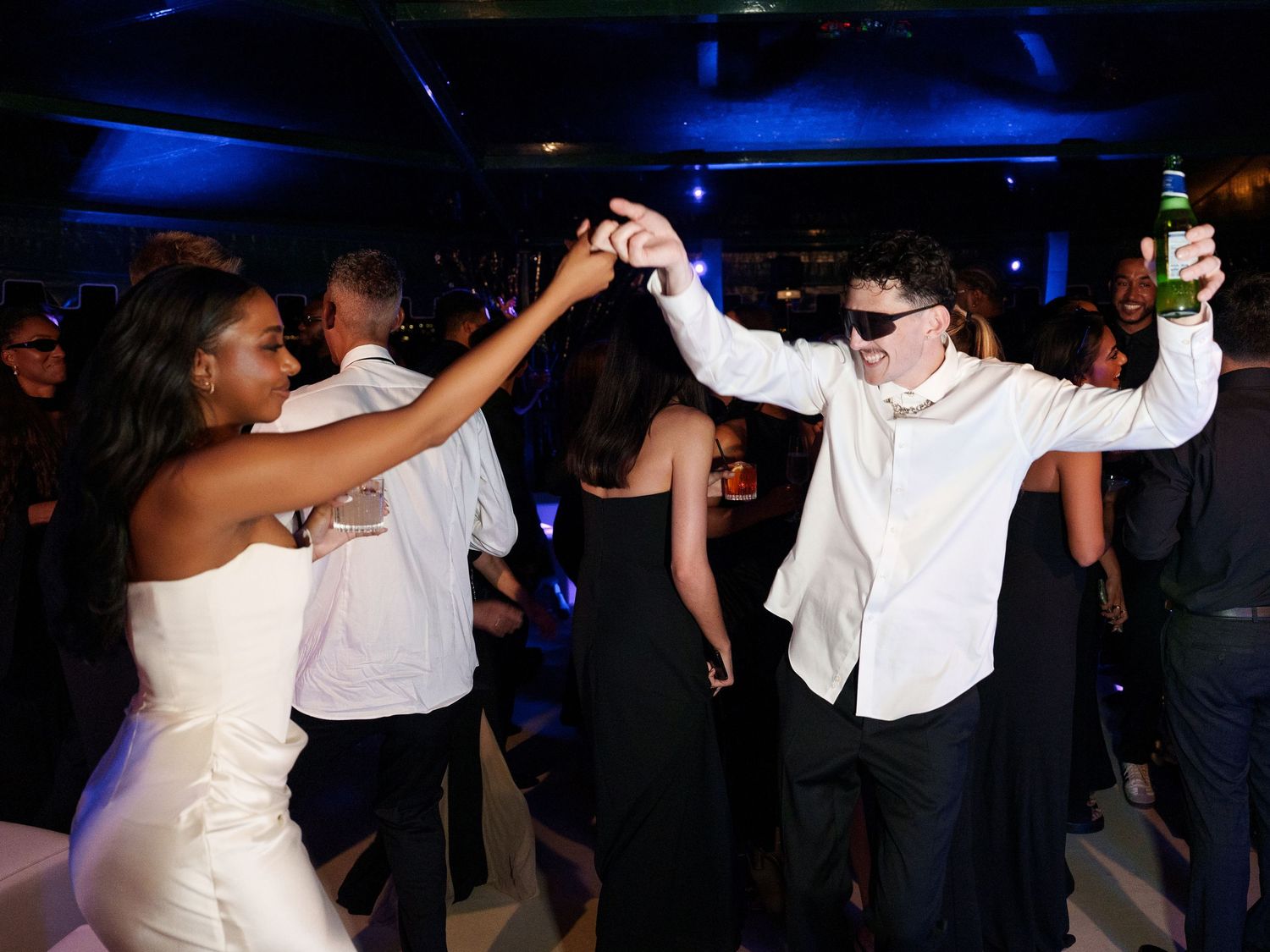 Wedding reception dance floor filled with guests enjoying themselves under blue lighting.