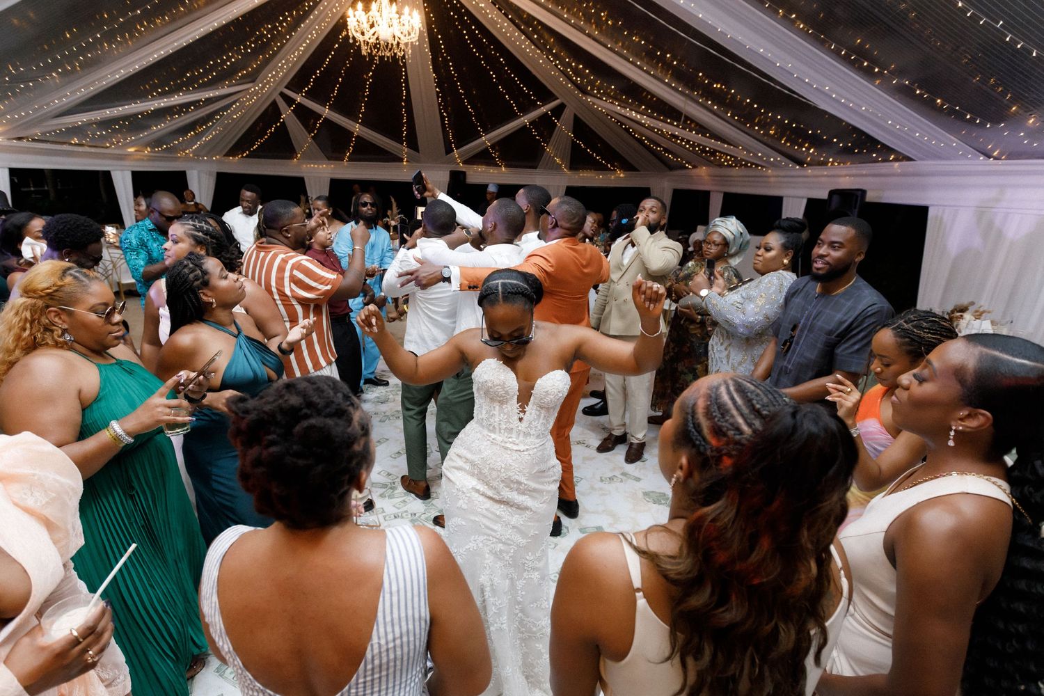 Wedding guests surround the bride on the dance floor during an energetic reception celebration.