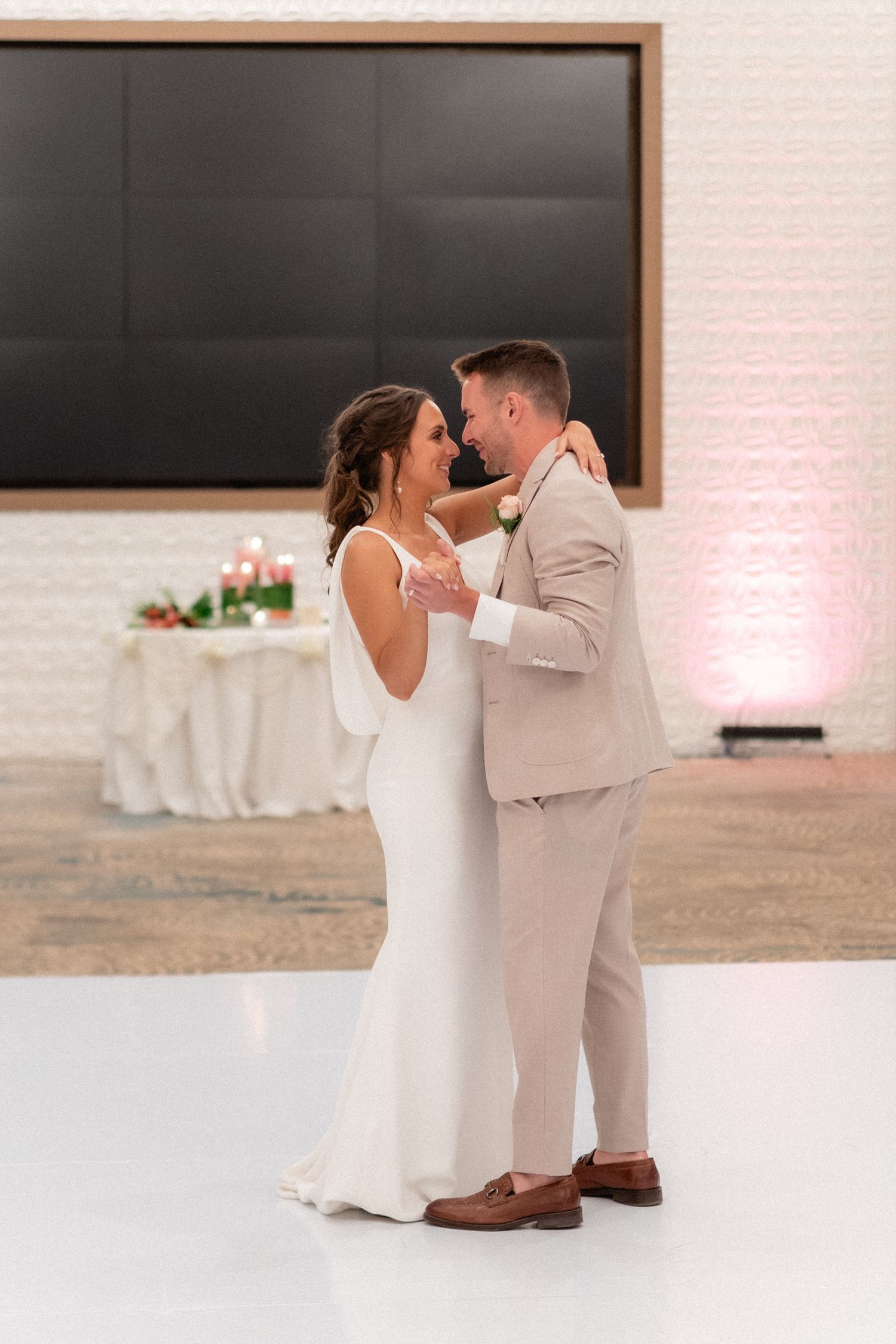 First dance moment on white dance floor in elegant reception venue.