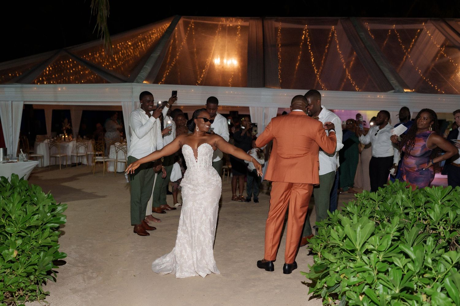 Wedding reception dance party under a white tent with string lights.