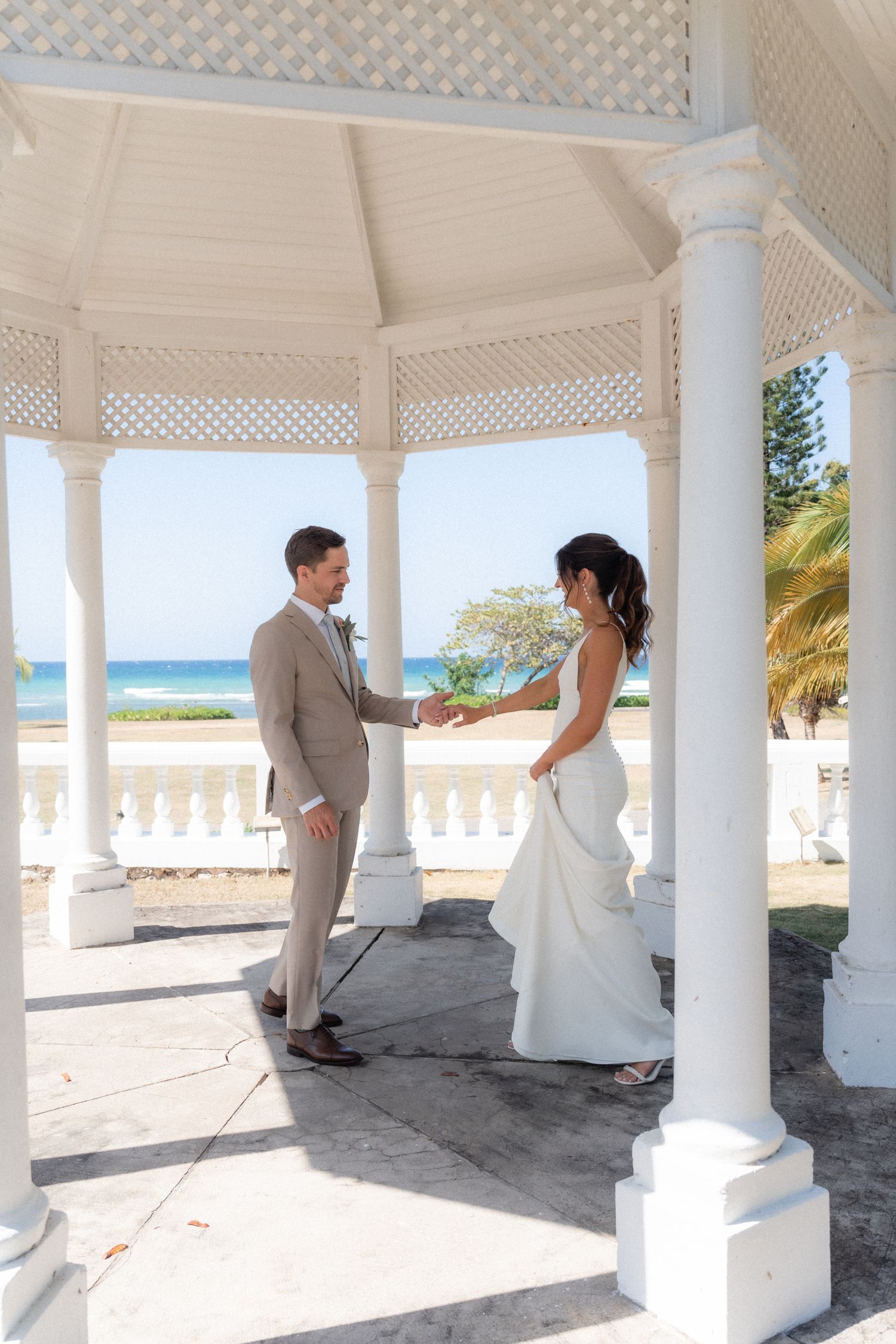 Couple shares intimate moment in seaside gazebo during destination wedding.
