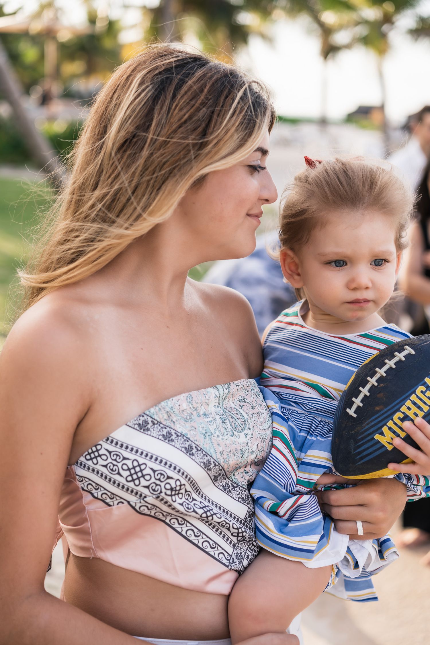 A tender moment on a sunny day with a small child holding a baseball glove outdoors.