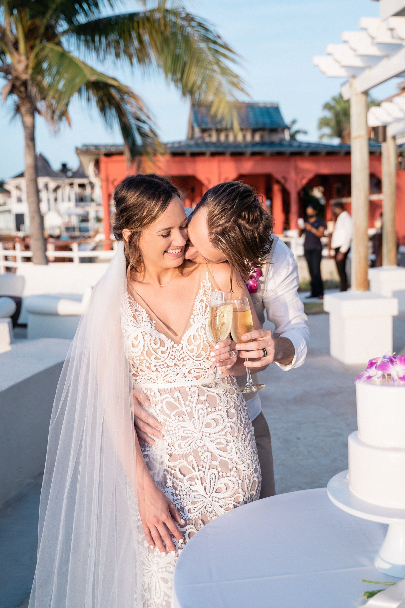 A celebration moment by a wedding cake with champagne glasses on an oceanfront terrace.