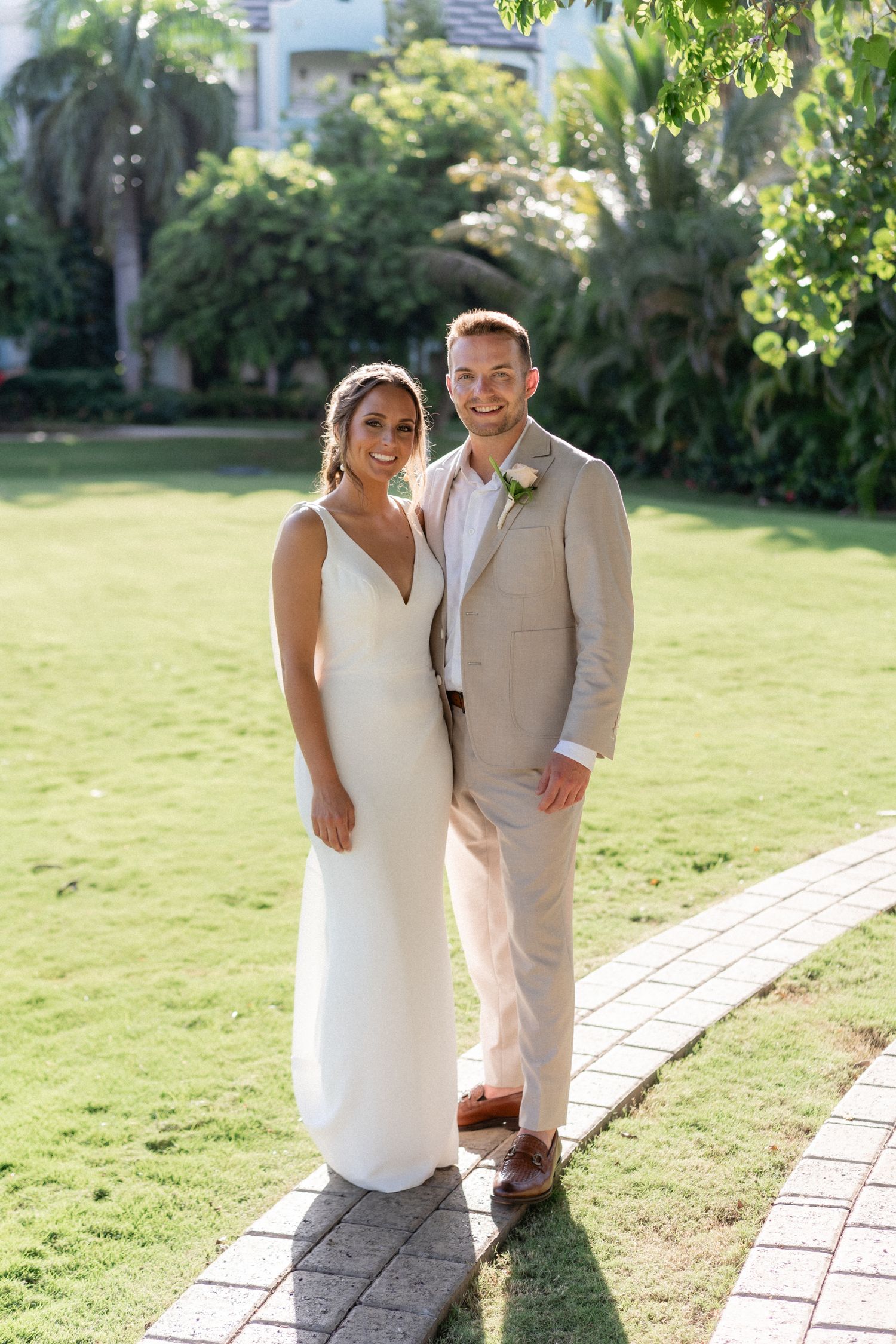 Newlyweds pose on a garden pathway at a tropical resort venue.