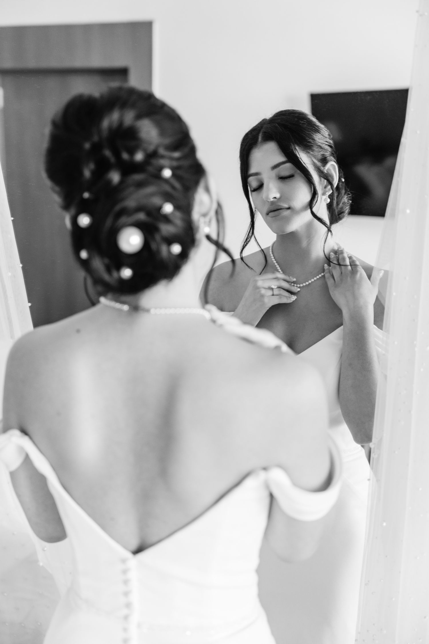 Black and white mirror reflection showing intricate wedding day hair styling.