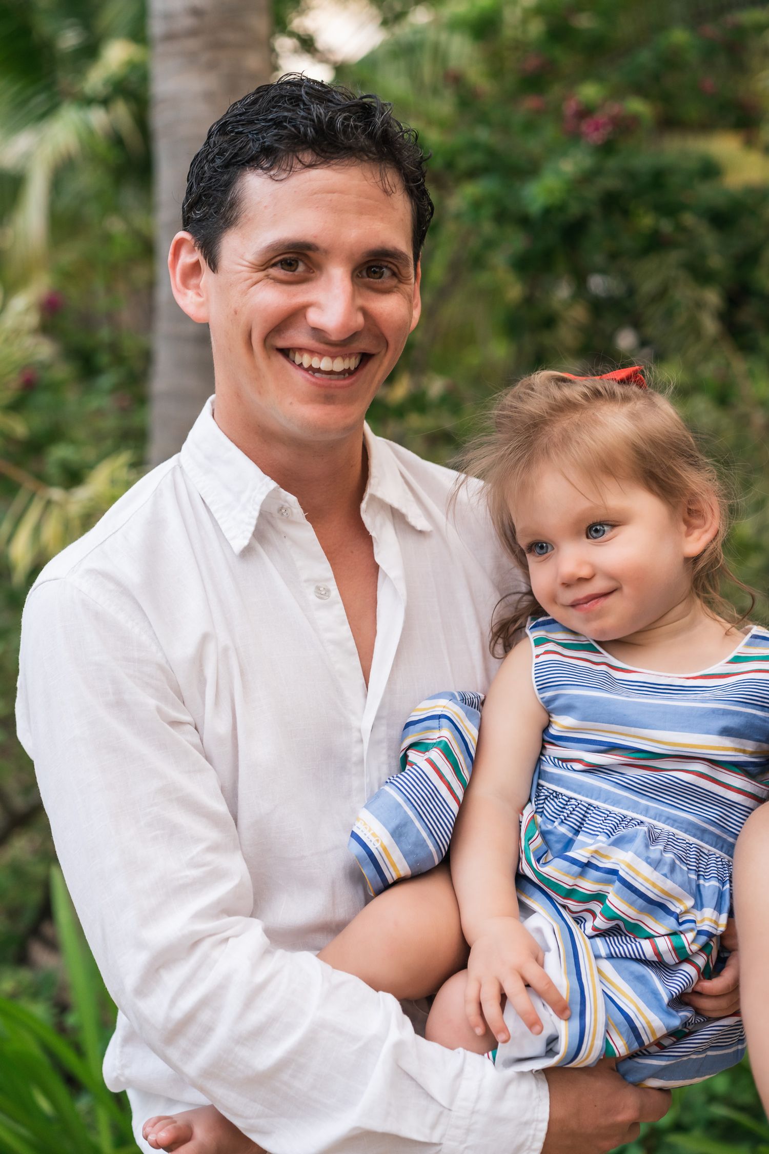 Warm portrait in tropical garden setting with coordinated blue and white outfits.