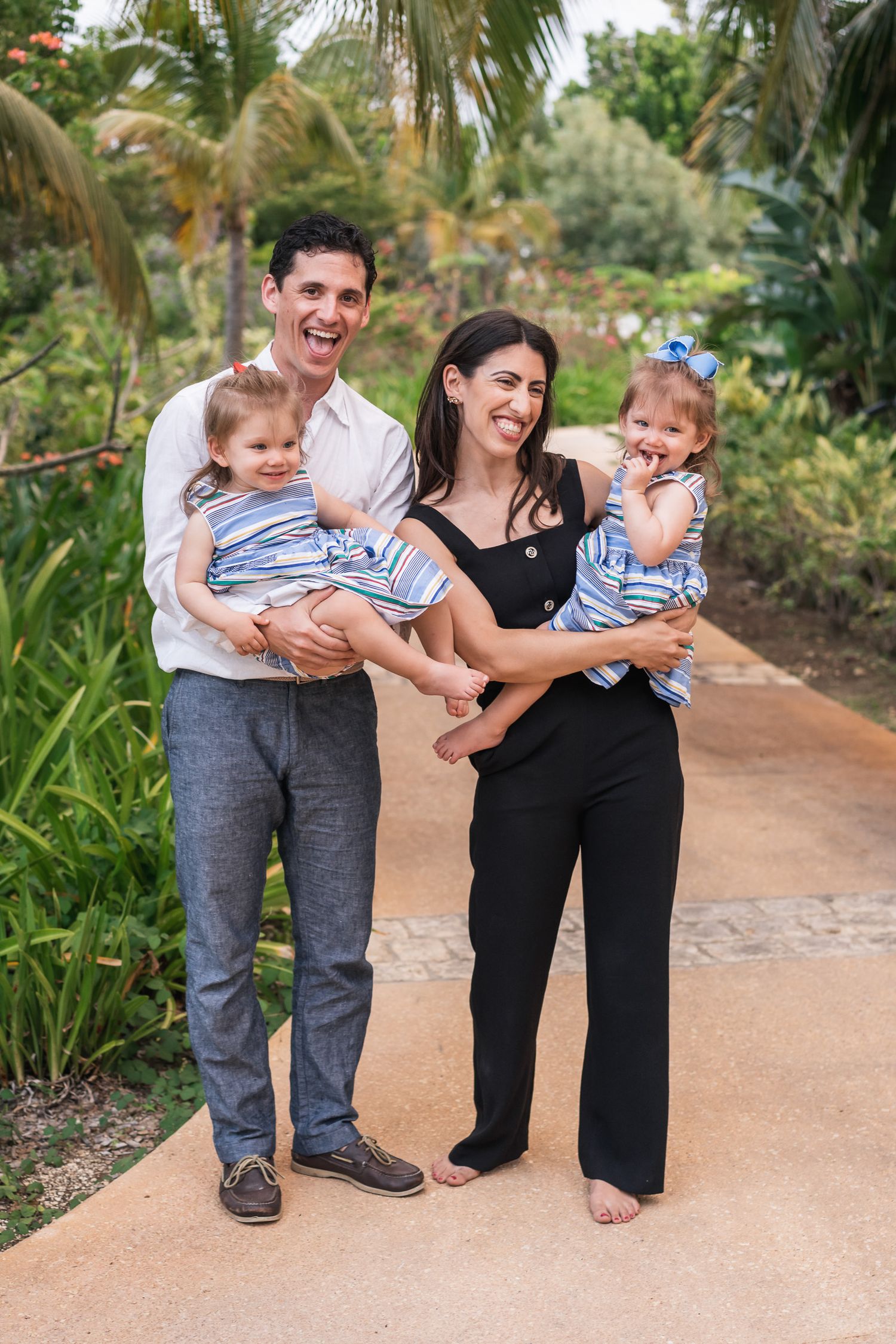 Family sharing joyful moment together on tropical garden path wearing coordinated outfits.