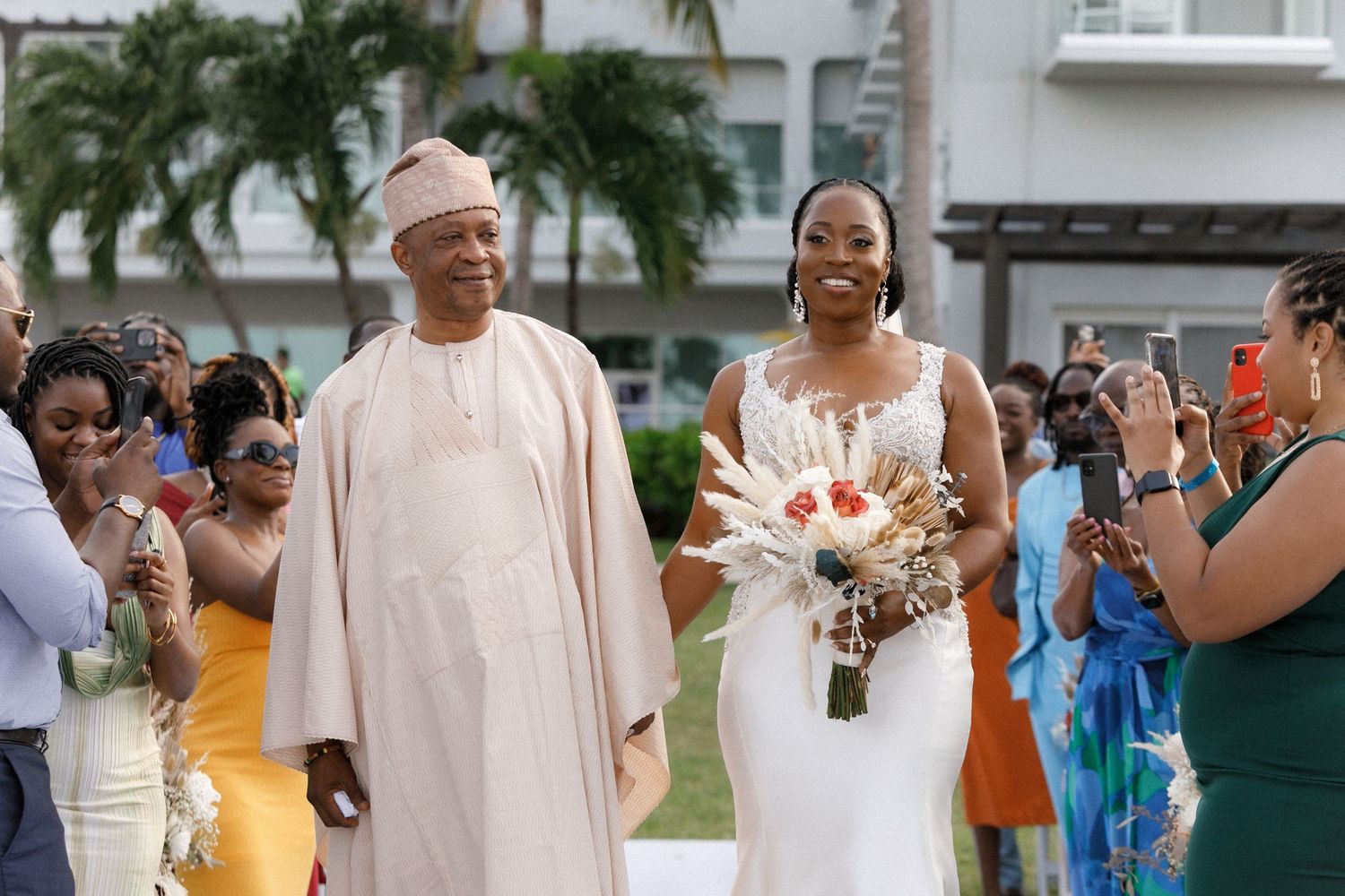 A celebratory outdoor wedding ceremony scene with tropical palm trees in the background.